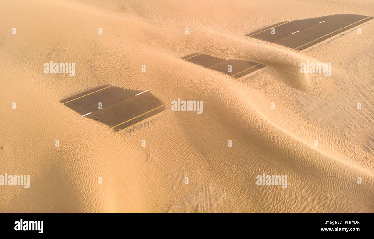 Le dune di sabbia che copre una strada vicino a Dubai Foto Stock