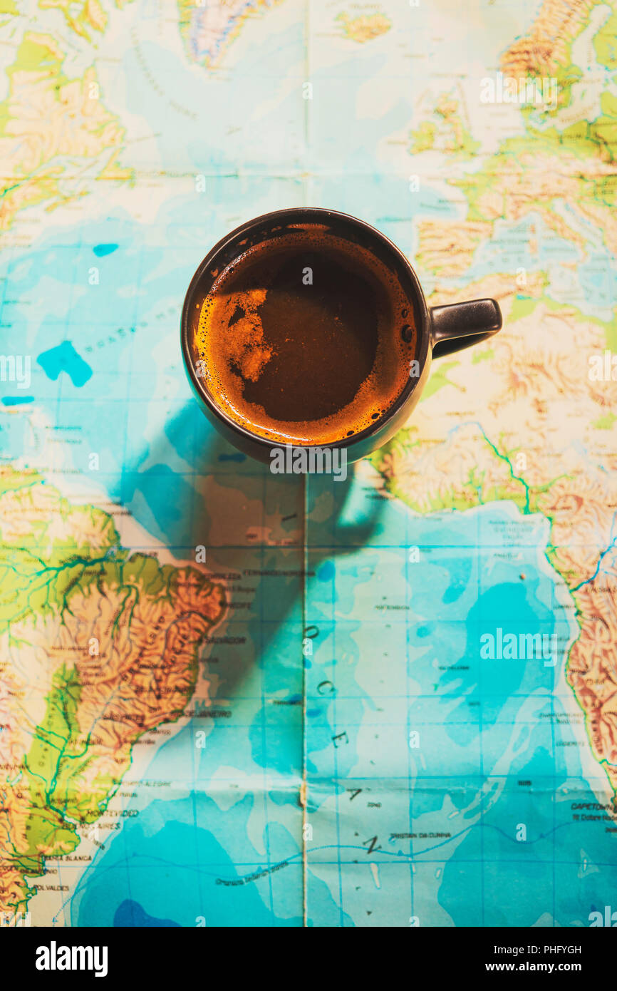 Bella tazzina di caffè con la mappa del mondo in background; immagine concettuale di viaggio viaggi planante con mappa del mondo; viaggi sfondo correlati Foto Stock