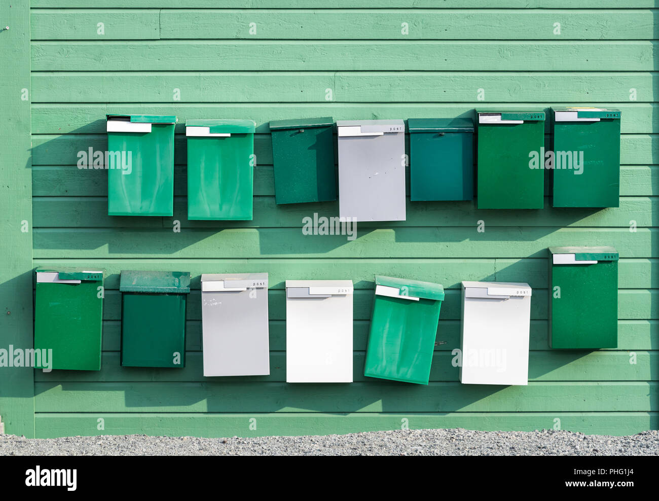 Un gruppo di caselle di posta di colore verde posto su una parete in legno, all'esterno. Foto Stock