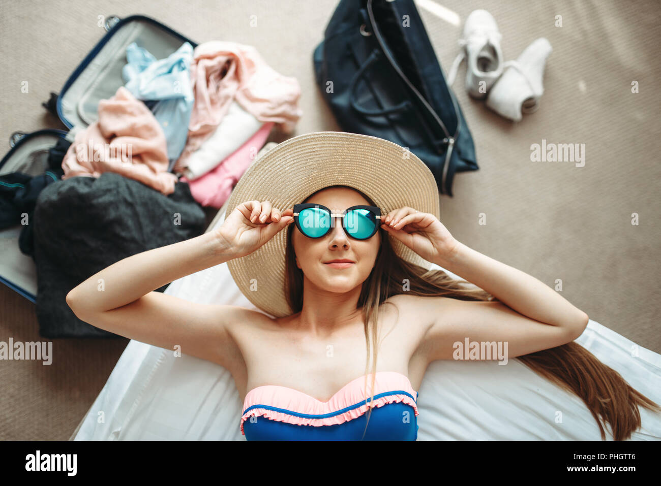Giovane donna si trova in costume da bagno e occhiali da sole, vista  dall'alto, ha