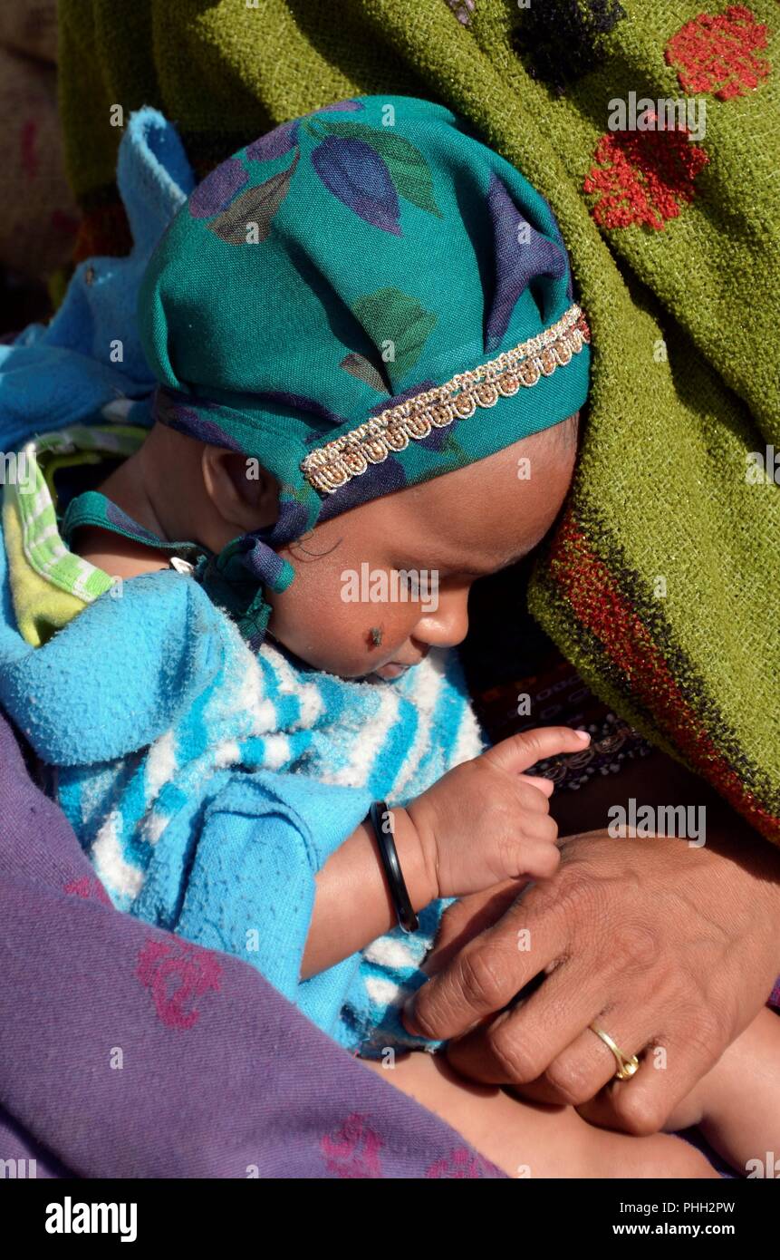 Baby swathed in coperte addormentato sulla sua madre di giro Foto Stock