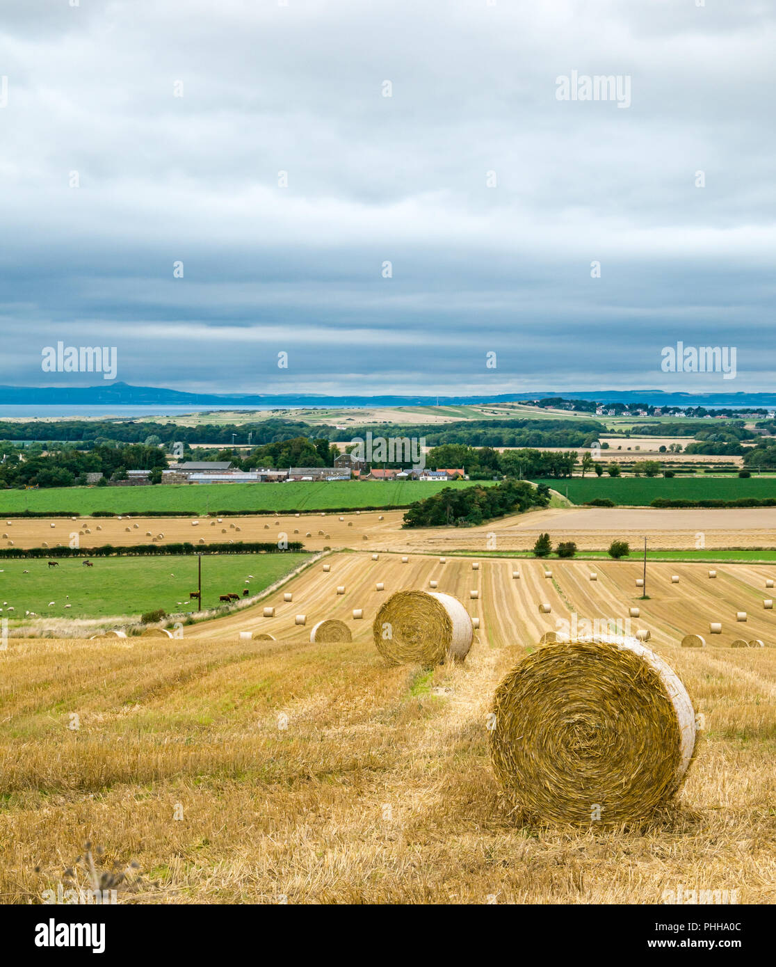 East Lothian, Scozia, Regno Unito, 1 settembre 2018. Regno Unito Meteo: un giorno nuvoloso nei campi agricoli della East Lothian campagna con round balle di fieno recentemente raccolte guardando verso il Firth of Forth Foto Stock