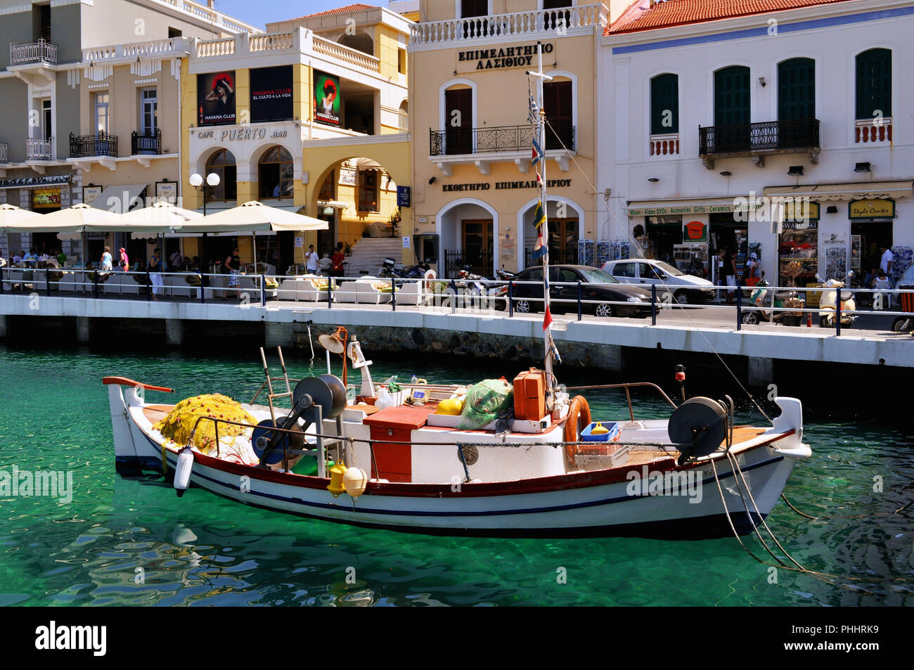 Agios Nicolaos, Creta / Grecia. La pesca tradizionale barca al Lago di Voulismeni. La gente di relax presso le caffetterie e negozi di souvenir Foto Stock