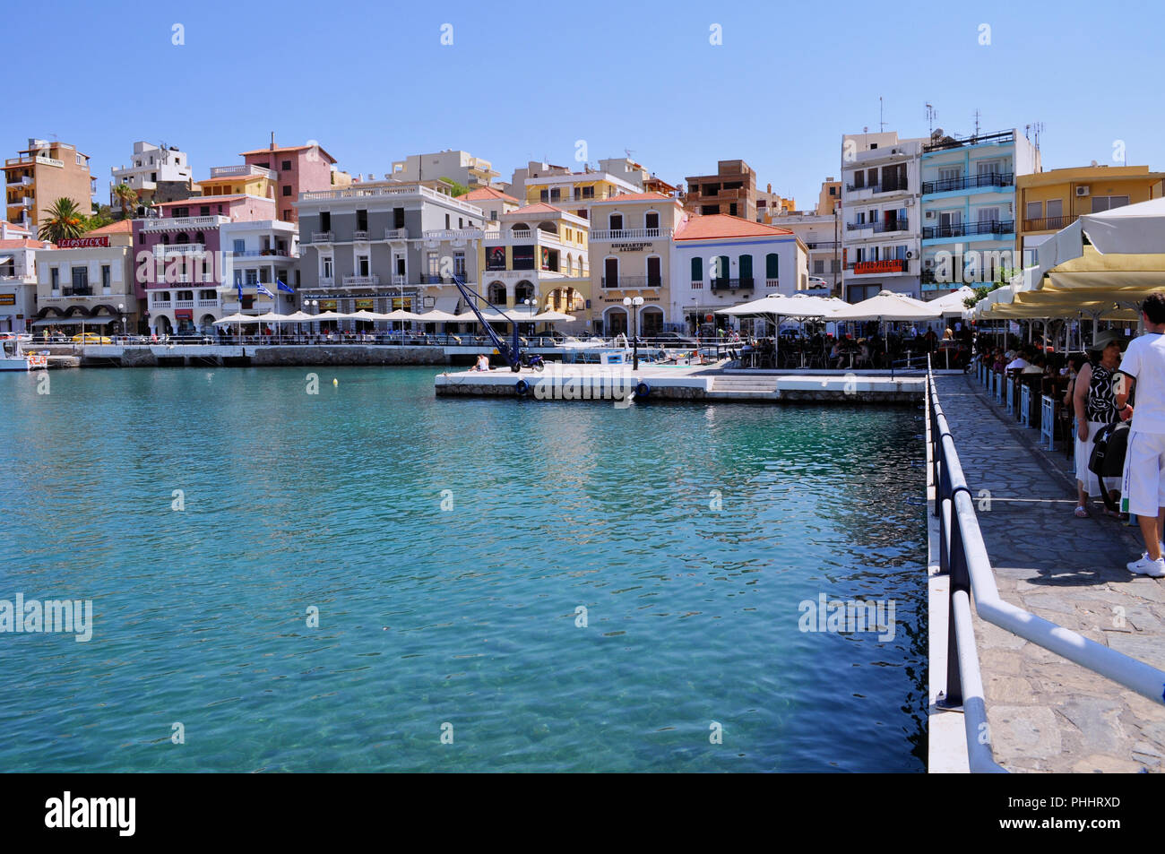 Agios Nicolaos, Creta / Grecia. Turisti e persone locali sono rilassanti presso il caffè accanto al mare di Agios Nikolaos cittadina Foto Stock