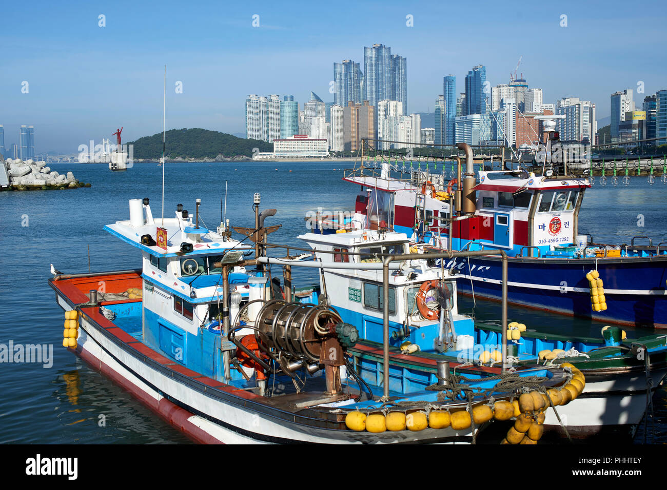 La Spiaggia di Haeundae, Busan, visto da sopra il piccolo porto di pesca con barche in primo piano e il Ponte di diamante e città in background. Foto Stock