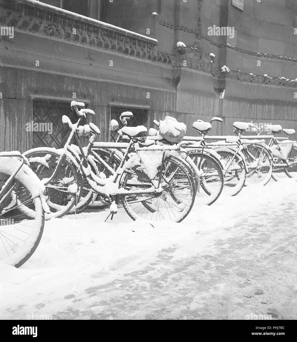 1950s biciclette. Le biciclette sono parcheggiate lungo il marciapiede in una giornata di inverni innevati. Svezia 1950. Foto Kristoffersson AY59-5 Foto Stock