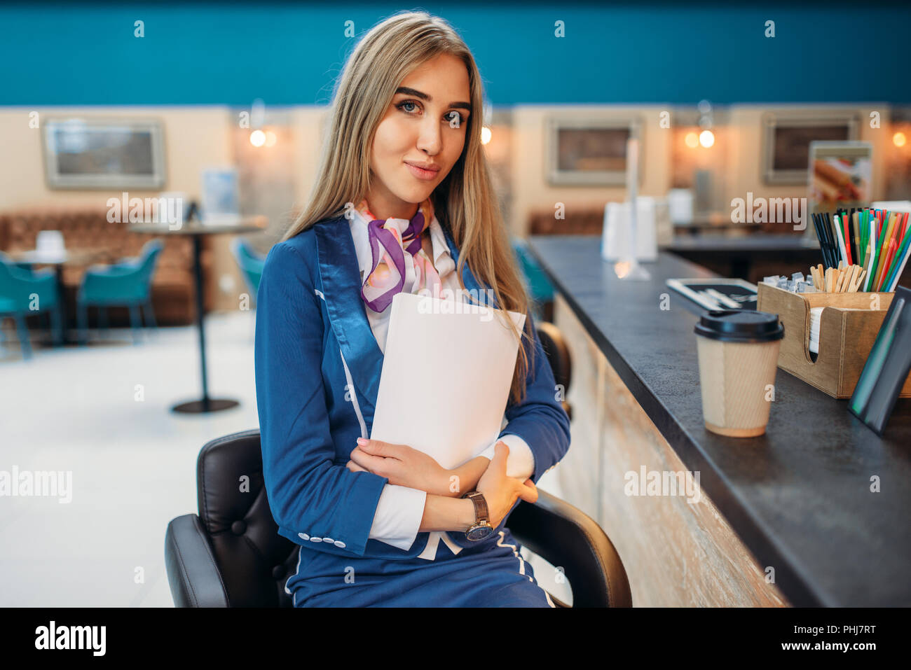 Hostess si siede al bancone del bar in aeroporto cafe. Hostess beve caffè nella zona di partenza, assistente di volo nella zona attesa, aviatransportations Foto Stock