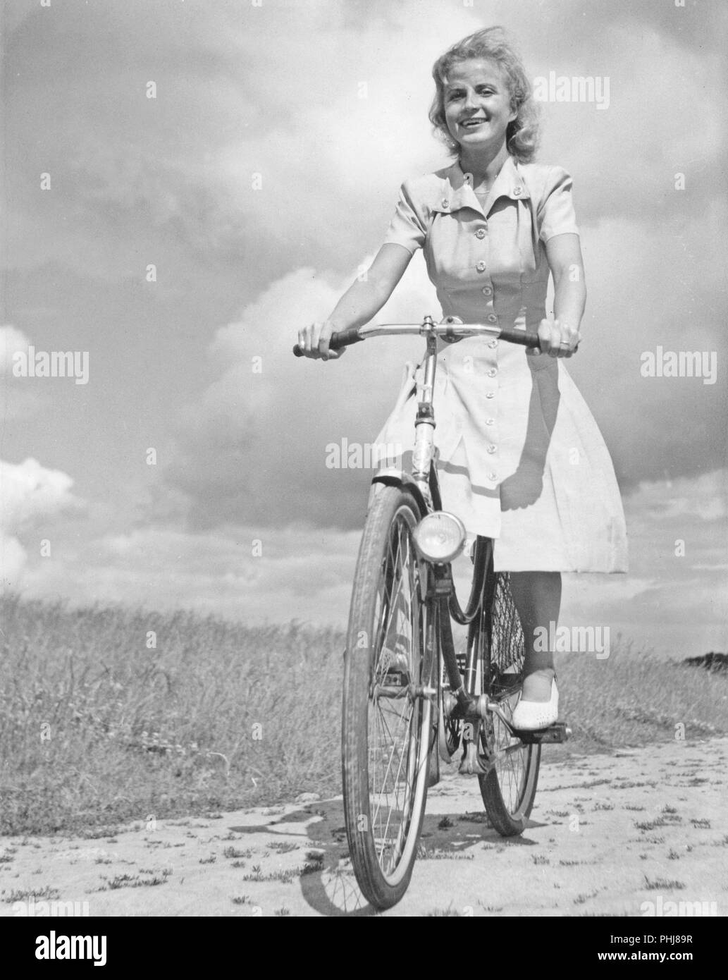 1940s donna su una bicicletta. Un sorridente ragazza su una bicicletta donna in una giornata di sole. La Svezia 1946 Foto Stock