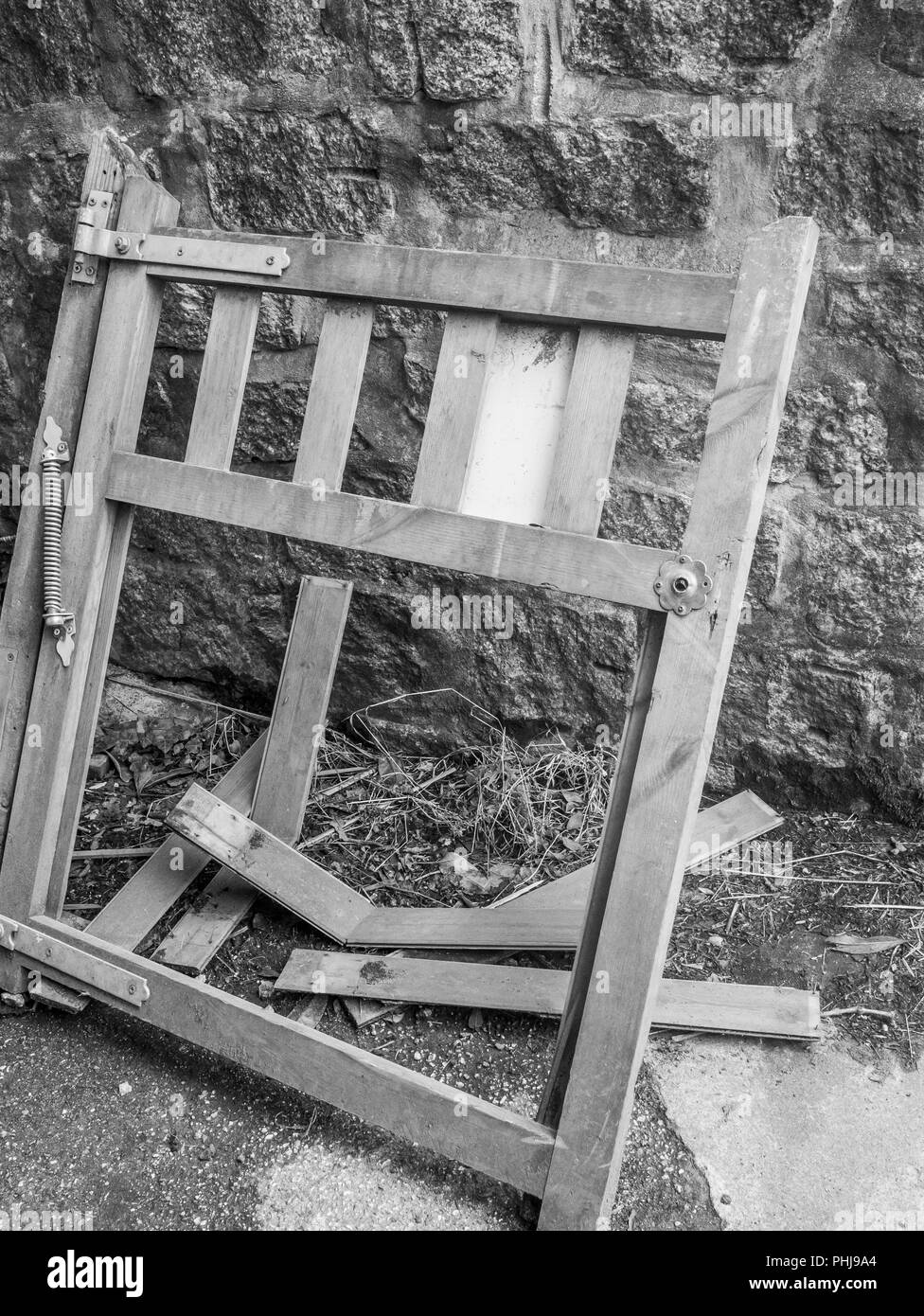 Rotto / fracassato garden gate sostennero contro il muro di pietra. Foto Stock