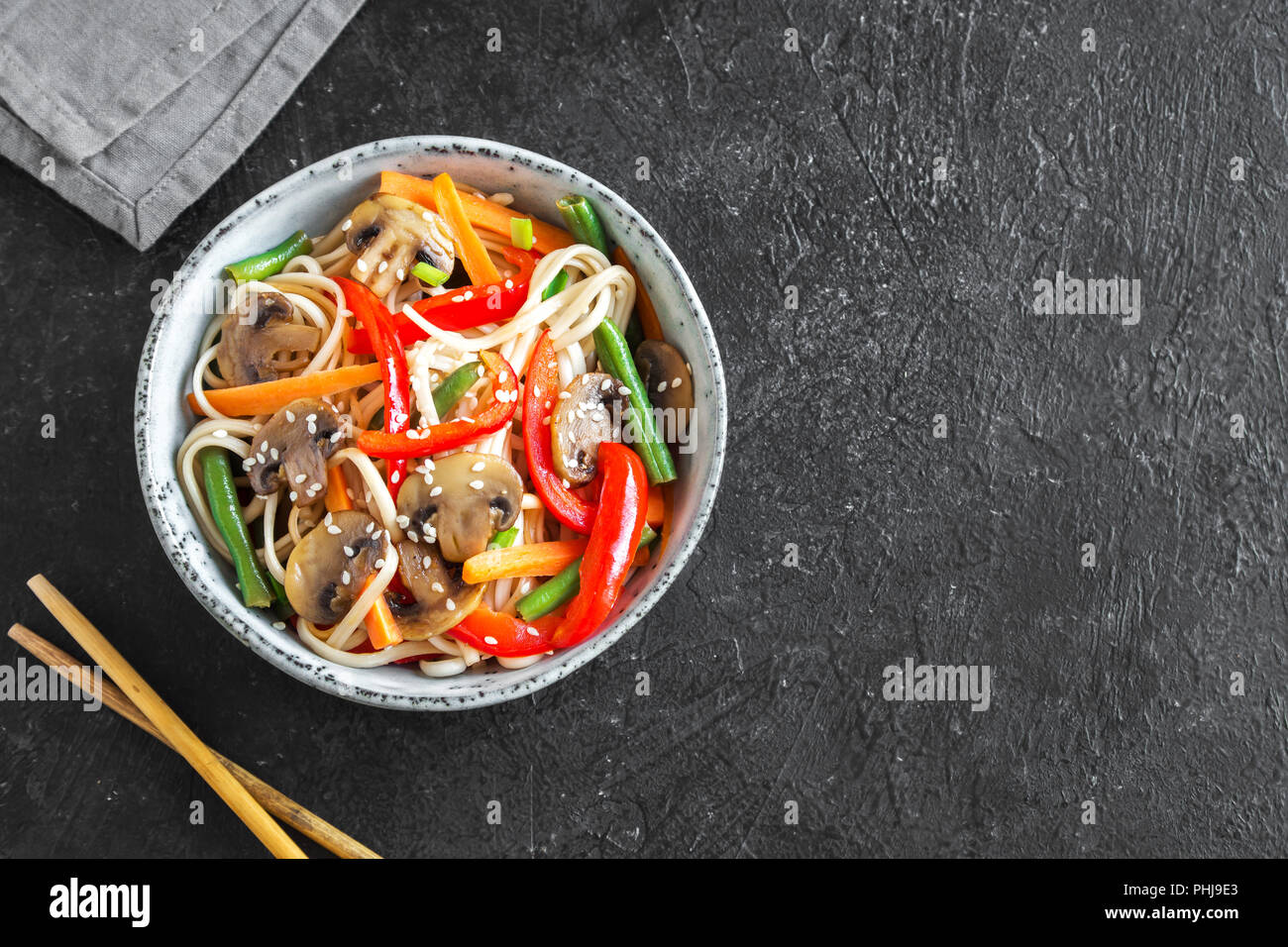 Stir fry con udon tagliatelle, funghi e ortaggi in vaso. Asian vegane cibo vegetariano, pasto, STIR FRY su sfondo nero, copia dello spazio. Foto Stock