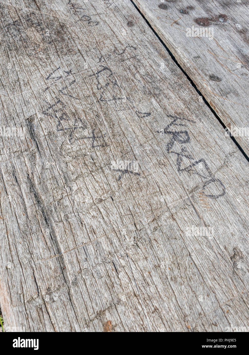 Varie iniziali incise nella parte superiore di un picnic in legno banco. Nozione di lasciare il vostro marchio". Foto Stock