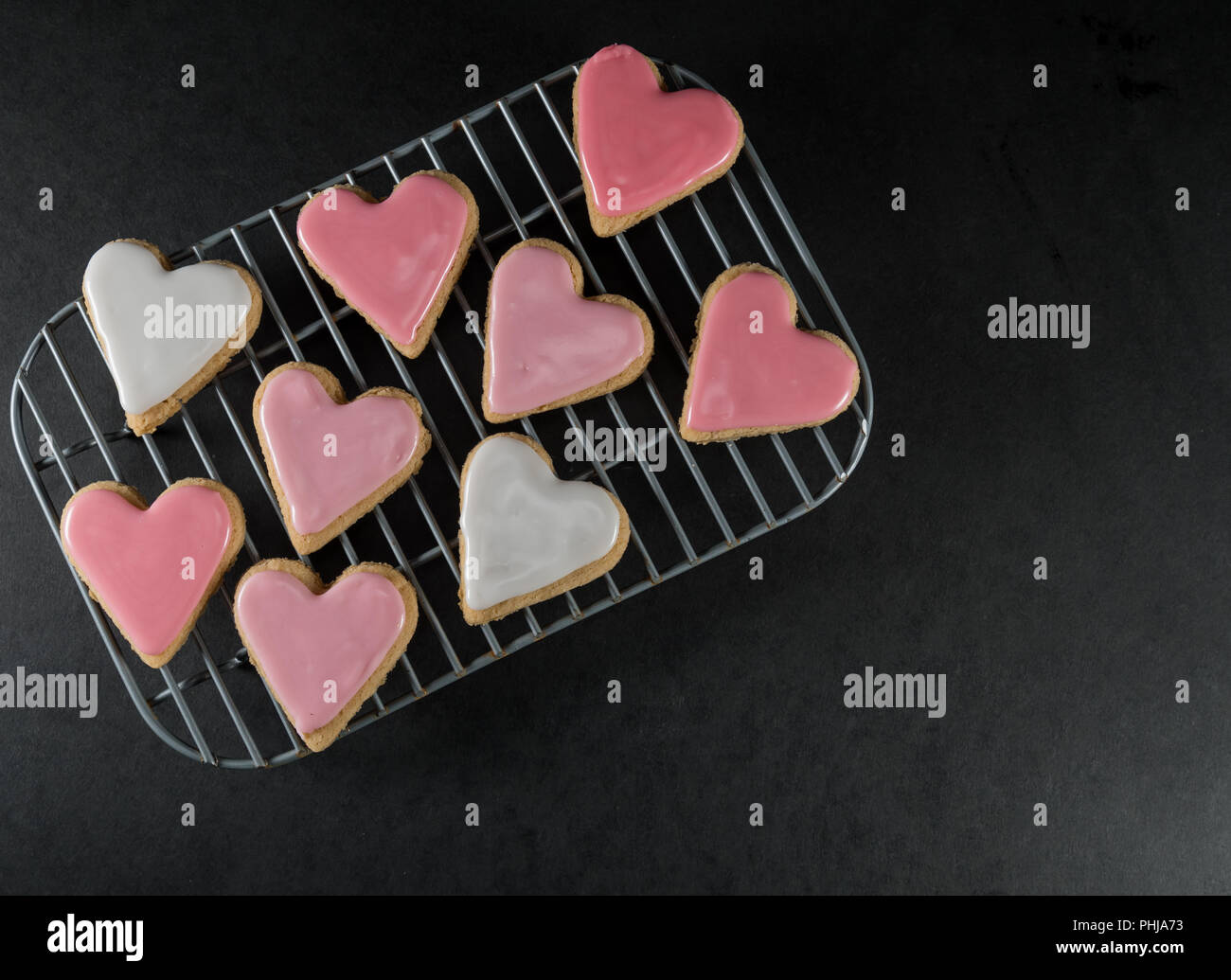 Piccolo cuore smerigliato cookie sul raffreddamento per rack su superficie di ardesia Foto Stock