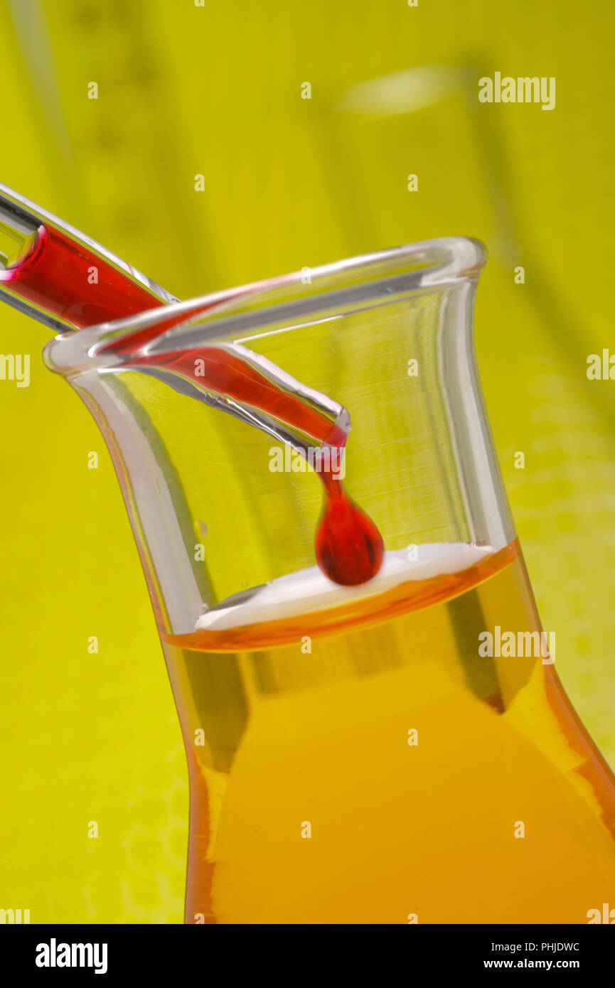 Goccia di liquido rosso è caduta nel bicchiere del laboratorio Foto Stock