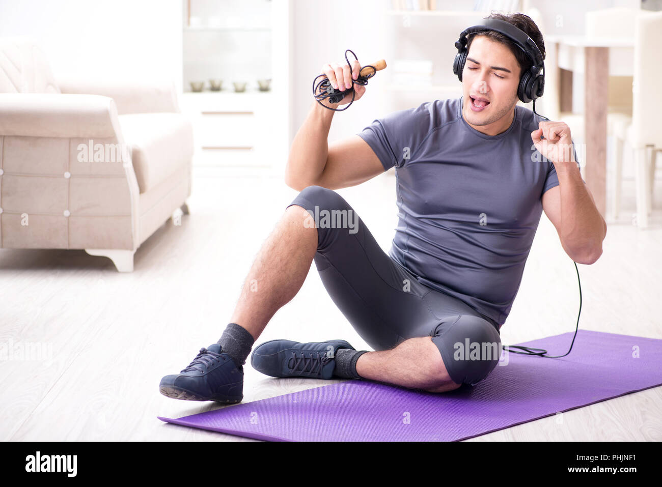L'uomo facendo sport a casa e ascolto di musica Foto Stock