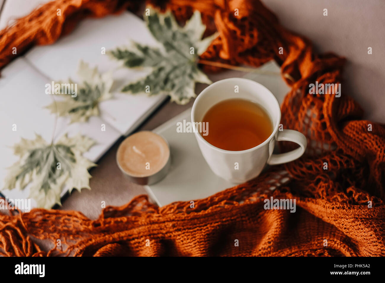 Autumn Fall concetto, notebook, sciarpa rossa, Autumn Leaf, candela e la tazza di tè caldo, hygge Foto Stock