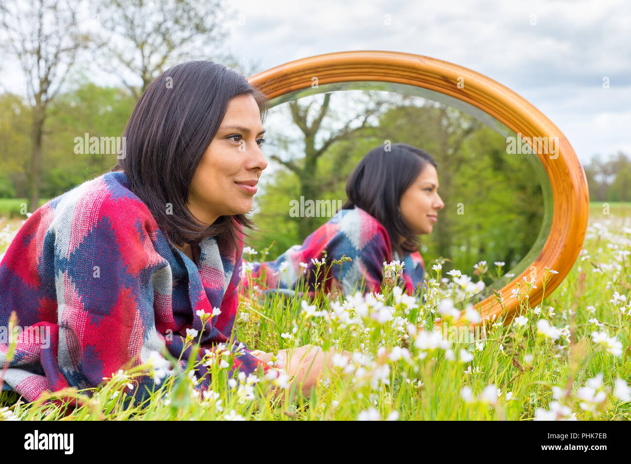 Donna sdraiata nel prato in fiore con specchio Foto Stock