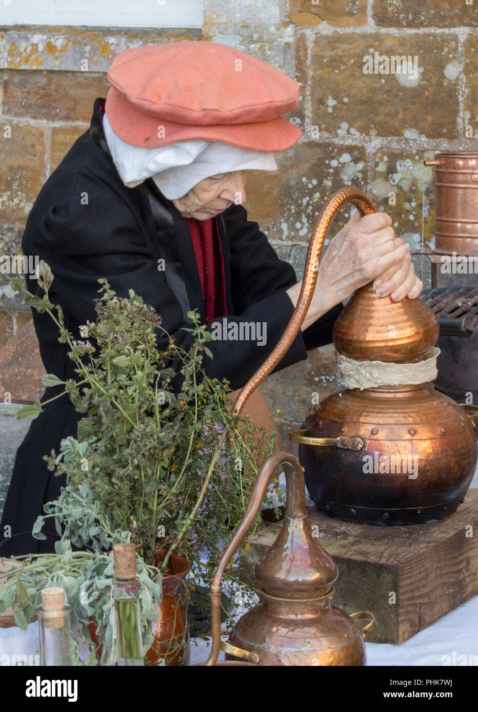 Una Donna vestita in periodo Tudor tradizionale abbigliamento abbigliamento o rimedi di miscelazione come un alchimista o erboristeria usando ingredienti naturali per la cura di mali. Foto Stock