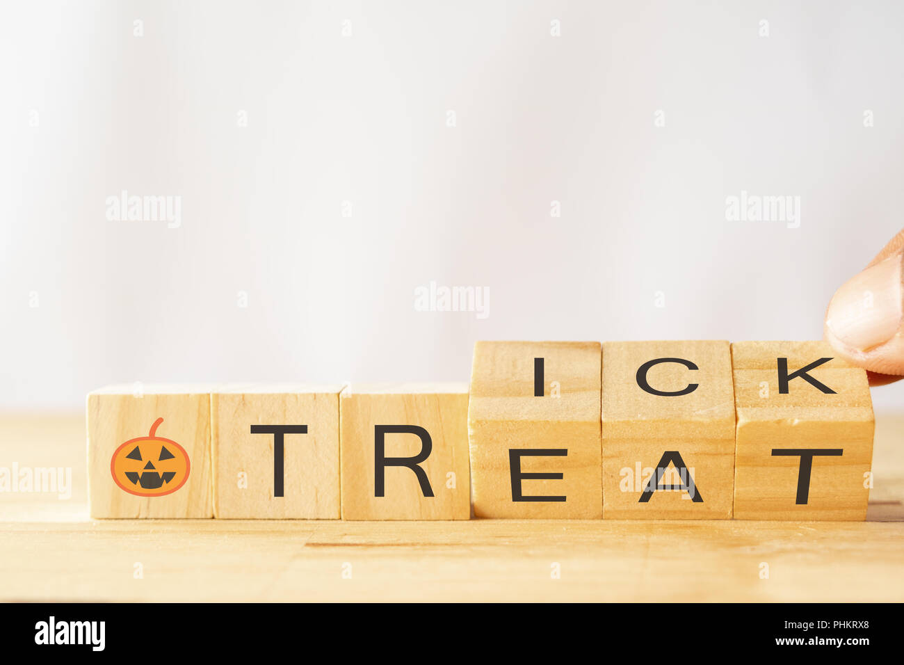 Halloween dolcetto o scherzetto concetto, man mano provare a capovolgere o ruotare i dadi in legno per cambiare la parola trucco per trattare e Jack o Lantern sui dadi di legno Foto Stock