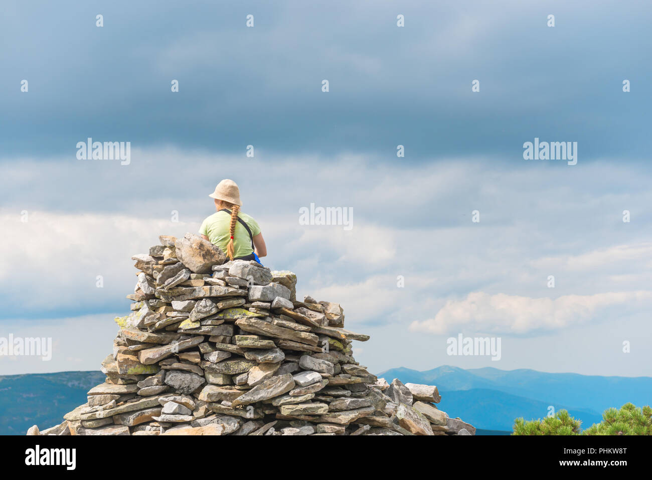 Giovane donna seduta sulla cima di una montagna Foto Stock