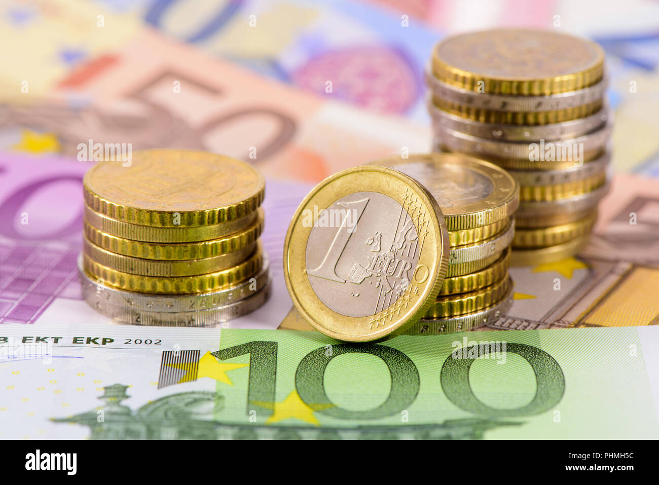 Molte le banconote della moneta europea che stabilisce al di sotto delle monete impilate Foto Stock