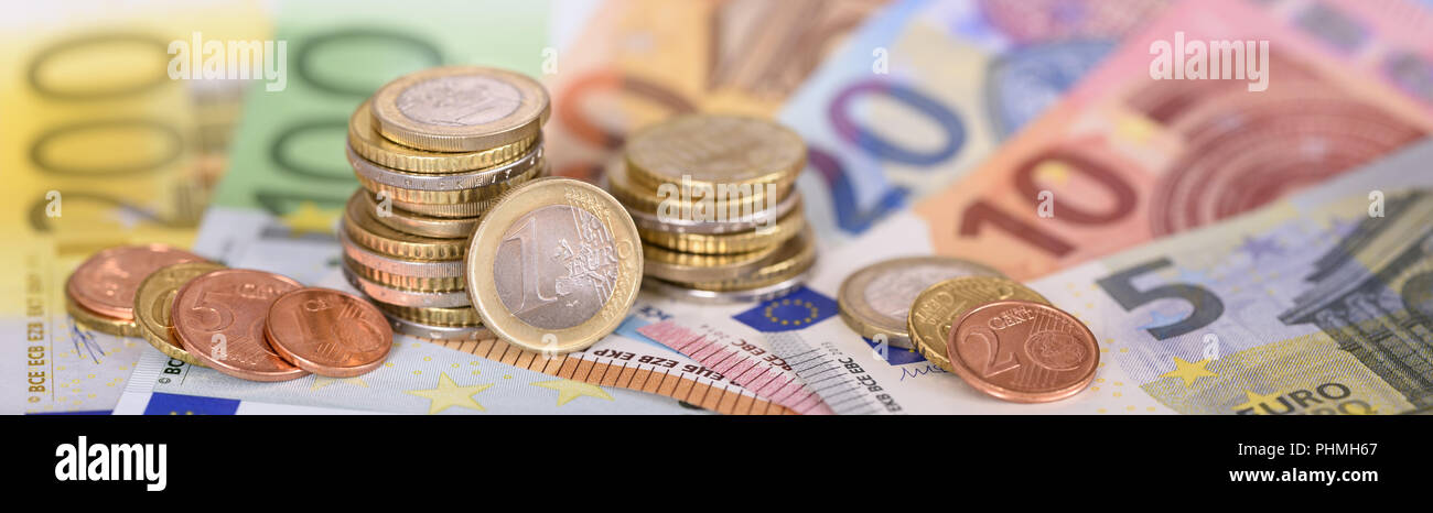 Molte le banconote della moneta europea che stabilisce al di sotto delle monete impilate Foto Stock