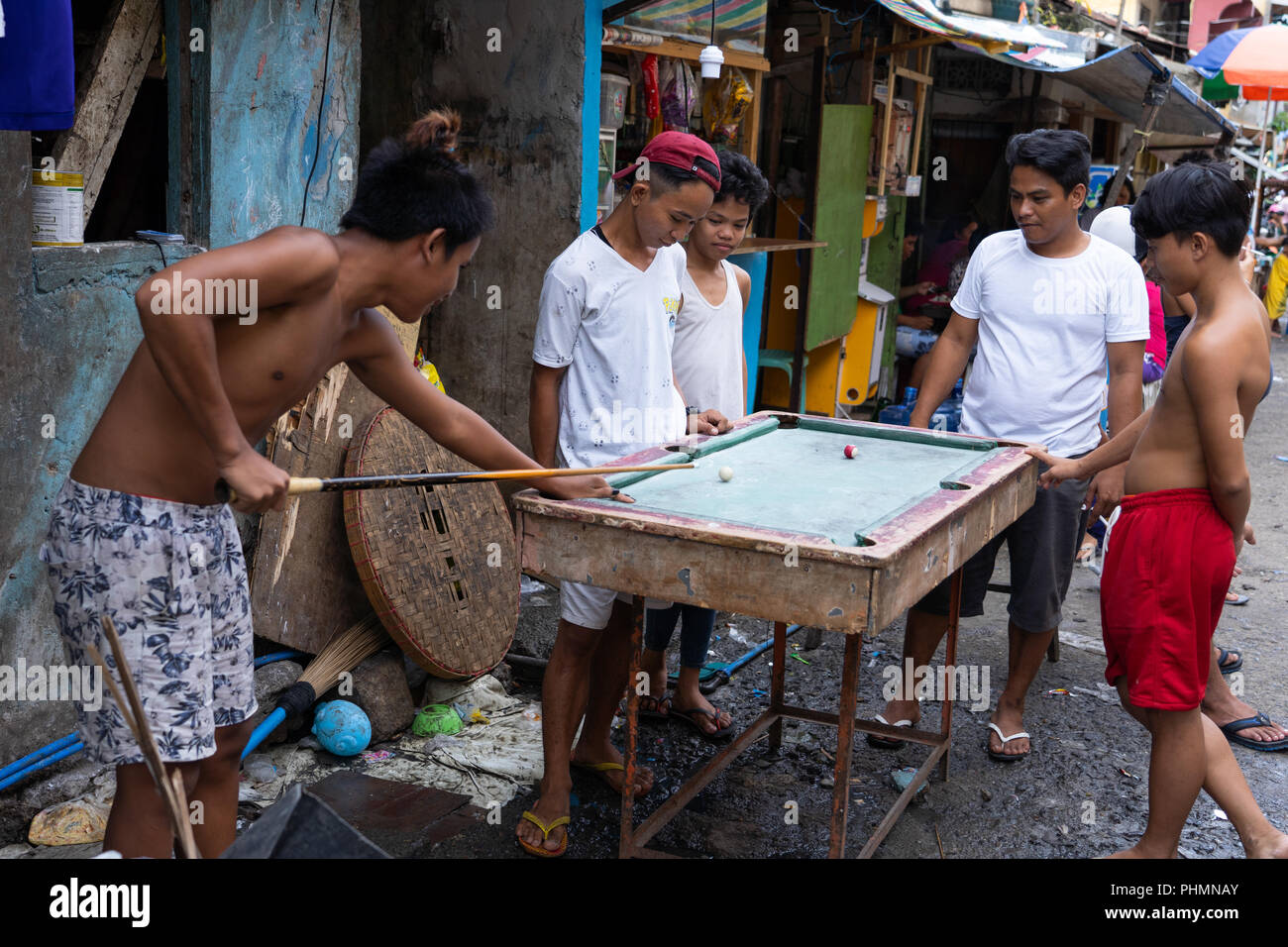 Un gruppo di giovani ragazzi filippini giocare una partita a biliardo su un tavolo improvvisato. Foto Stock