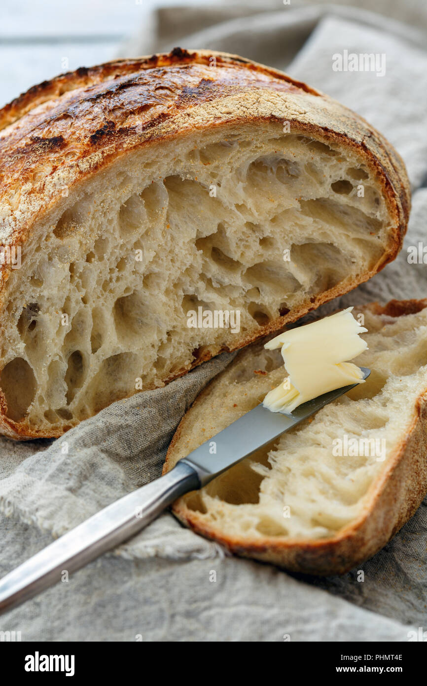 Tagliare una pagnotta di pane artigianale sulla pasta madre. Foto Stock