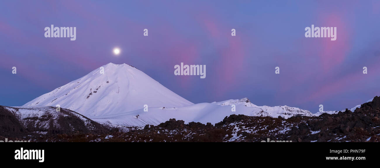 Panorama di luna piena sopra il Monte Ngauruhoe durante il sorgere del sole in inverno con la nuvola rosa Foto Stock