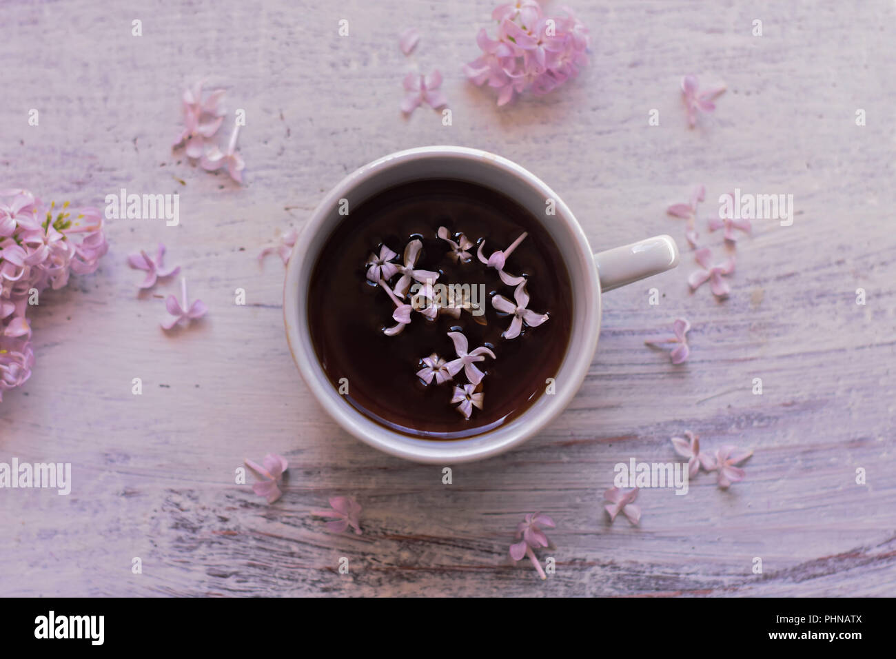 Viola fiori lilla e la tazza di tè sulla luce sullo sfondo di legno/ teatime/ molla sfondo/ accogliente a casa/ home decor a molla Foto Stock