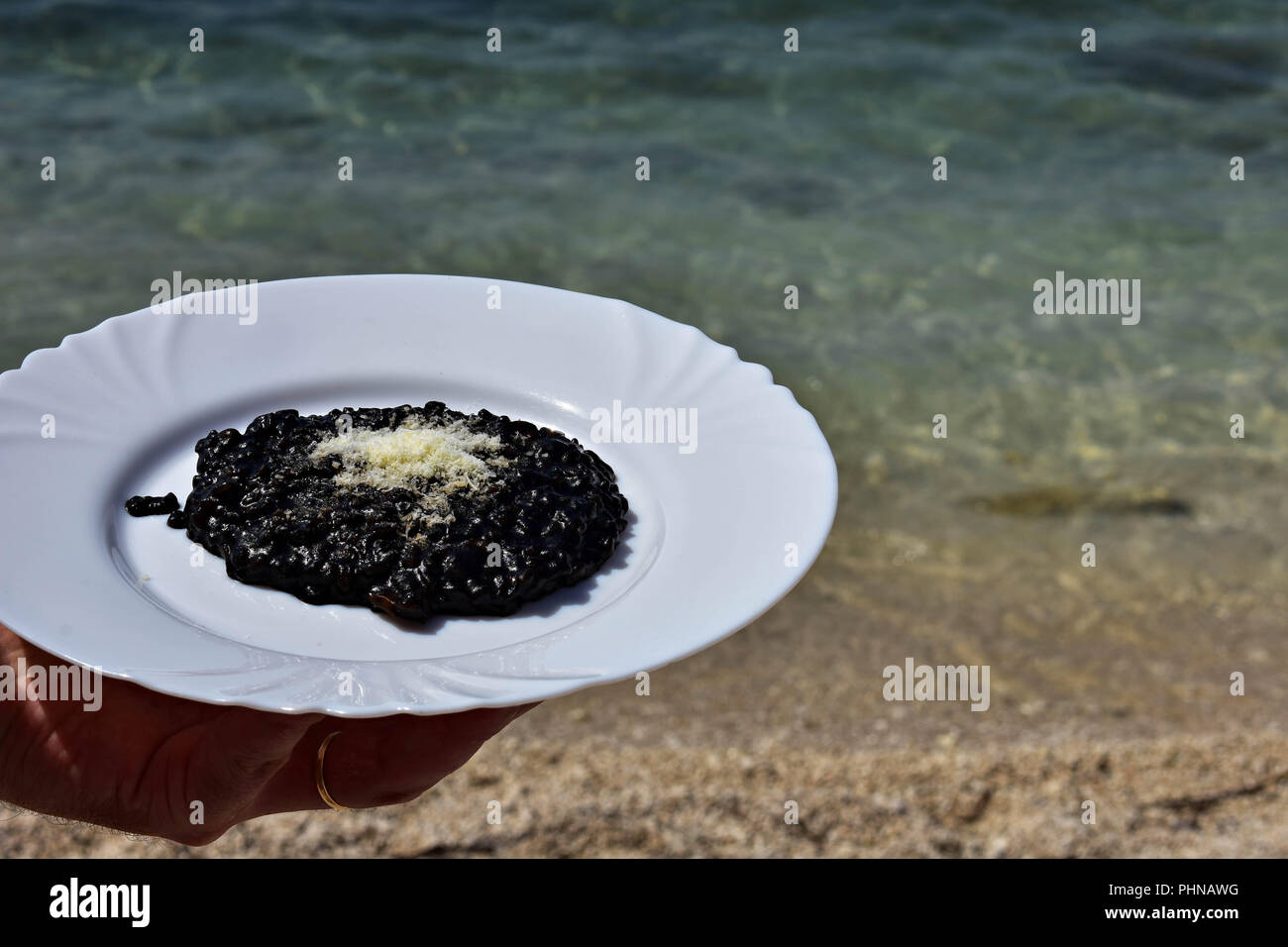 Nero deliziosi risotti serviti dal mare/ cameriere tenendo la piastra del risotto nero / cucina mediterranea Foto Stock