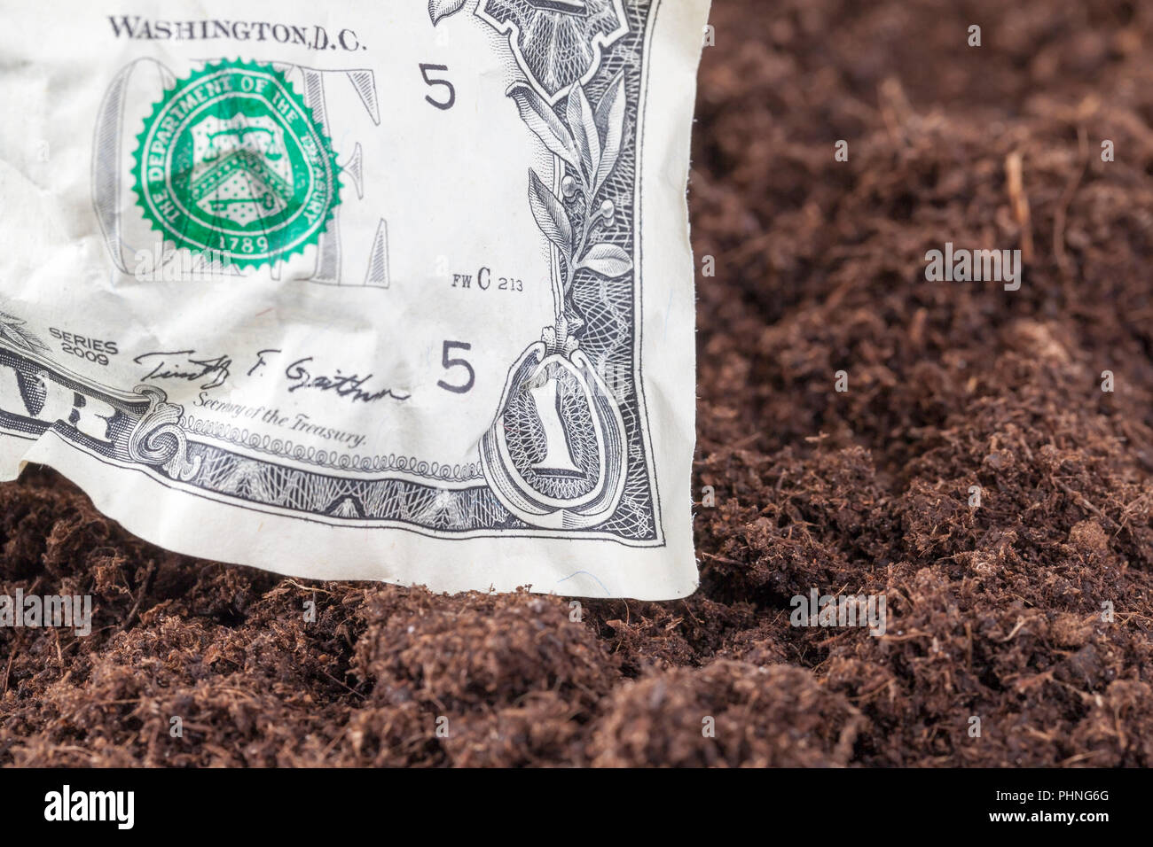 Uno accartocciata dollaro americano si trova sul terreno sporco sul campo, primo piano Foto Stock