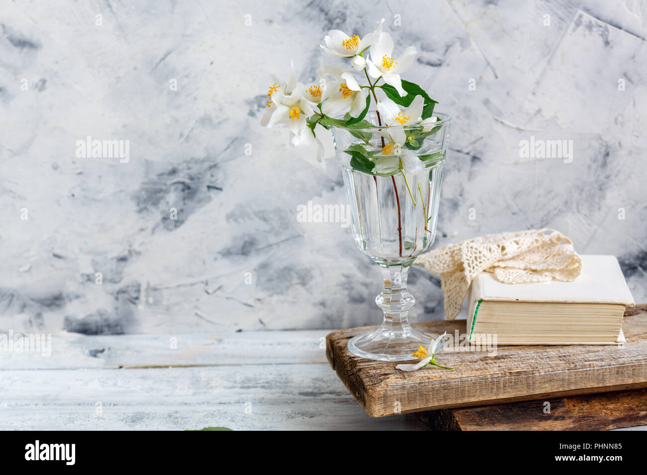 Rametti di Jasmine in un bicchiere e un vecchio libro. Foto Stock