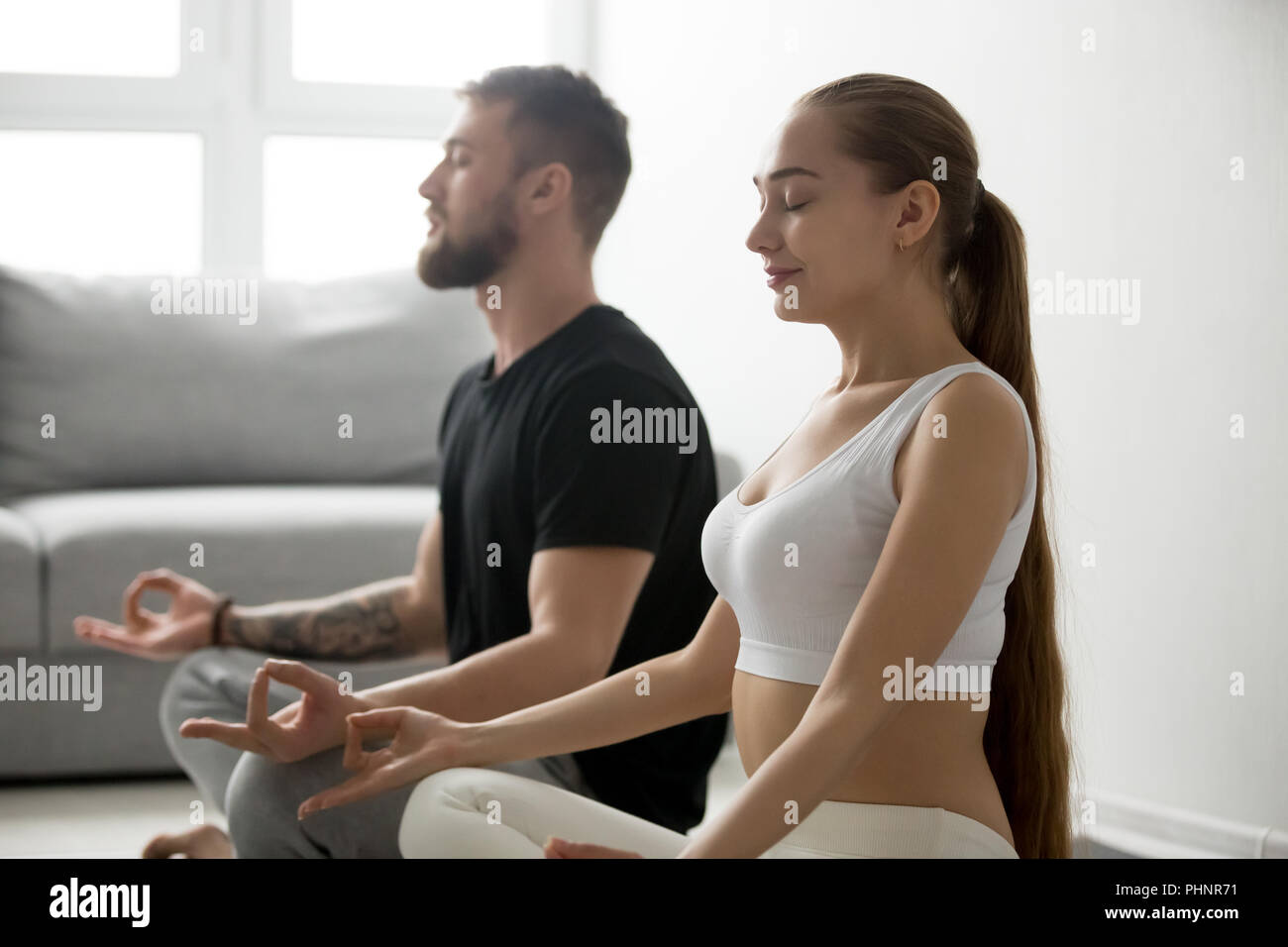 Calma giovane meditare nella posizione del loto a casa Foto Stock