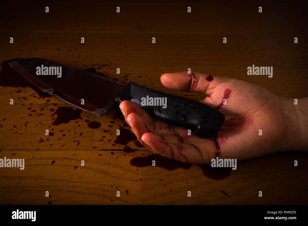 Il suicidio, omicidio o scena del crimine. La mano di una persona morta intriso di sangue in possesso di un coltello sul pavimento. Foto Stock