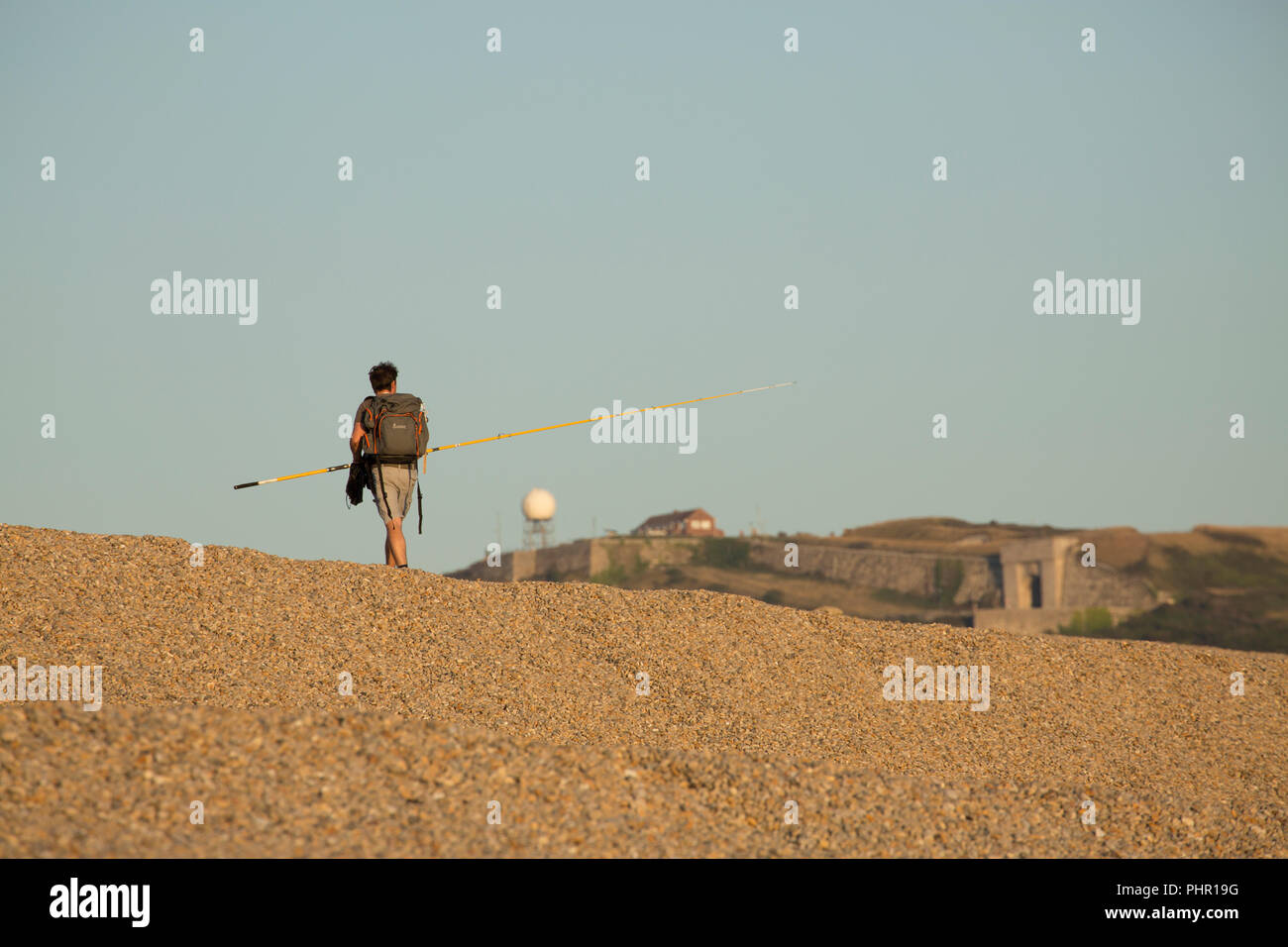 Un pescatore di sgombro voce per la casa nel tardo pomeriggio su Chesil Beach con l'isola di Portland dietro. Il Dorset England Regno Unito GB Foto Stock