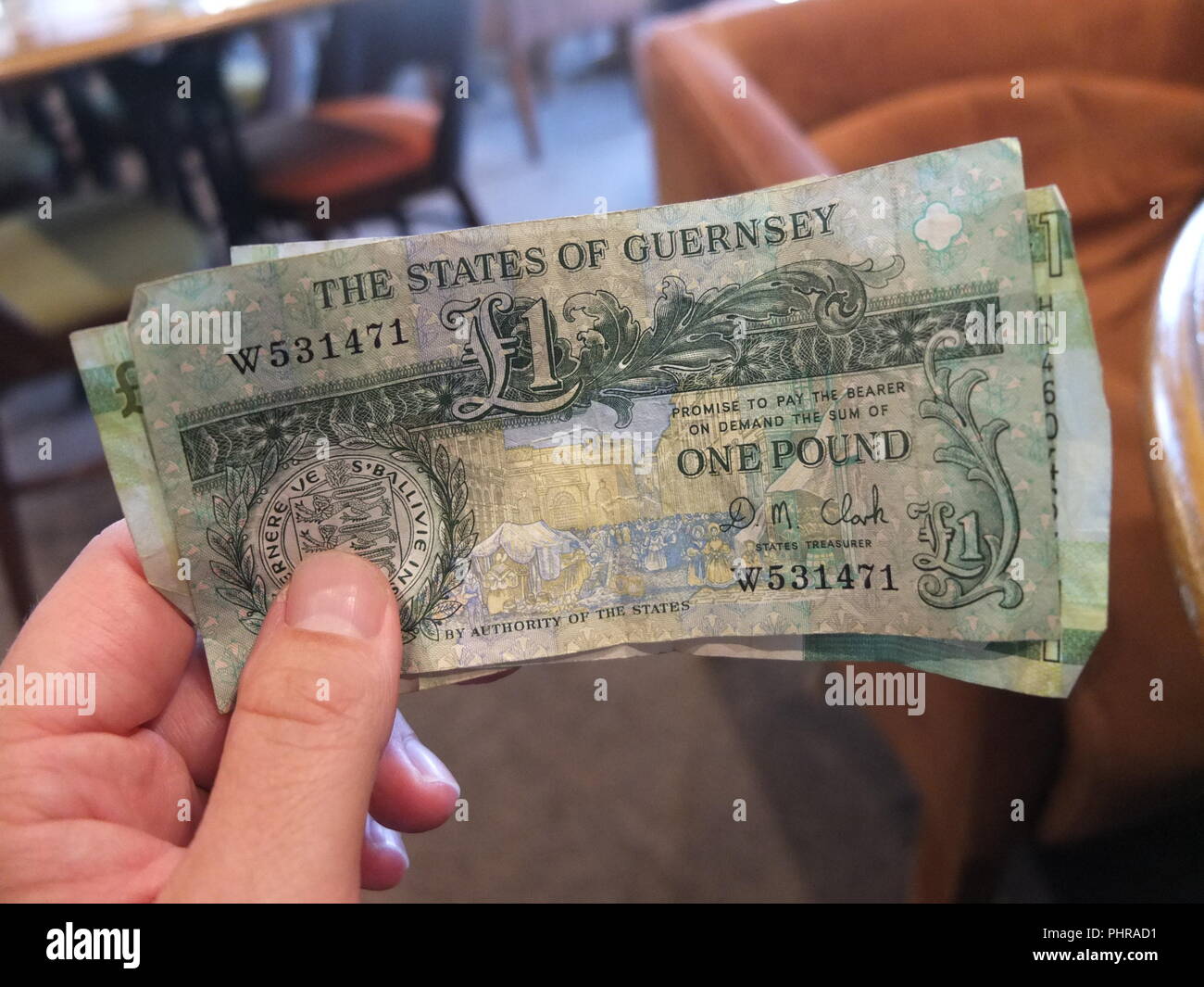 Maschio di mano azienda mazzetto di Guernsey Pound note con bar/ristorante sfondo, pound note sono ancora corso legale nelle isole del Canale della Manica Foto Stock
