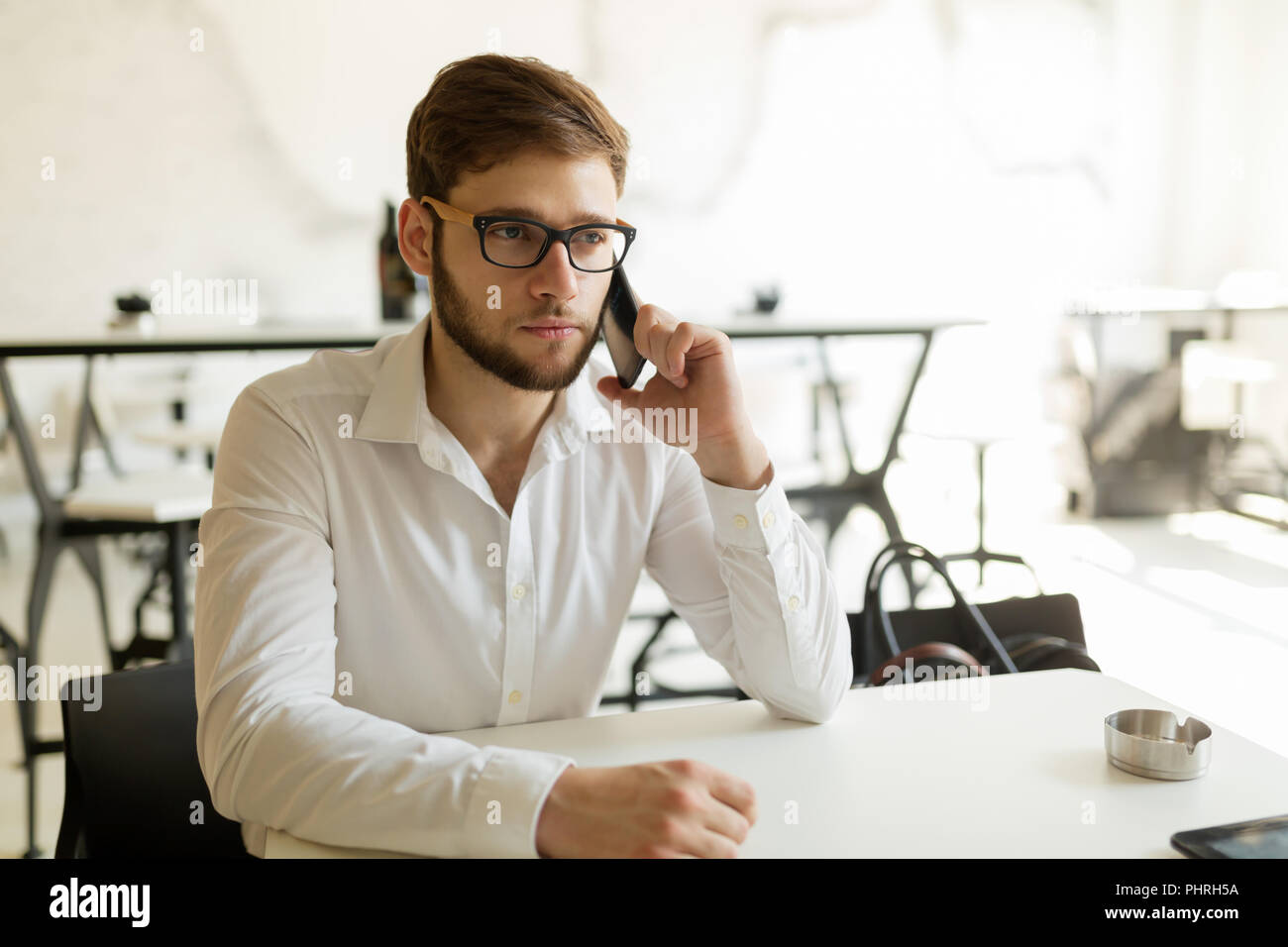 Pensieroso giovane imprenditore nel cafe usando il telefono Foto Stock