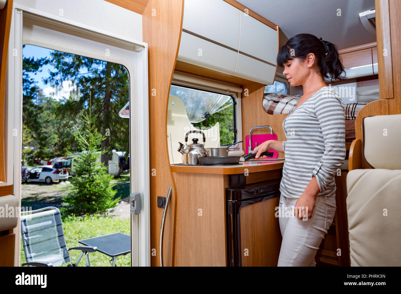 Donna cucinare in camper, camper RV interni. Vacanza per la famiglia in viaggio, viaggio vacanza in camper, caravan auto vacanza. Foto Stock