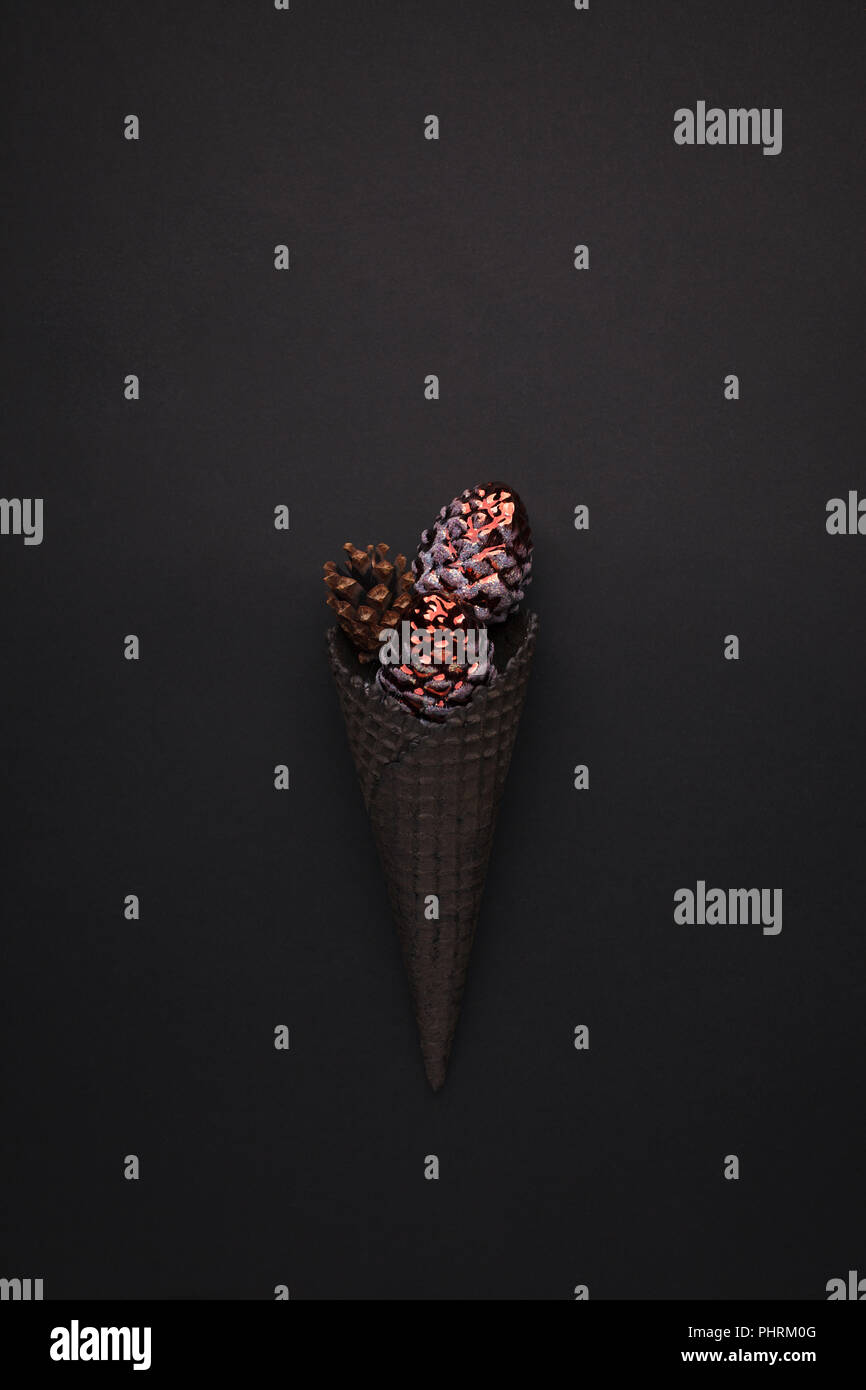 Nero cono gelato con chrismas anno nuovo decor e giocattoli su sfondo nero monocromatico closeup minima Foto Stock