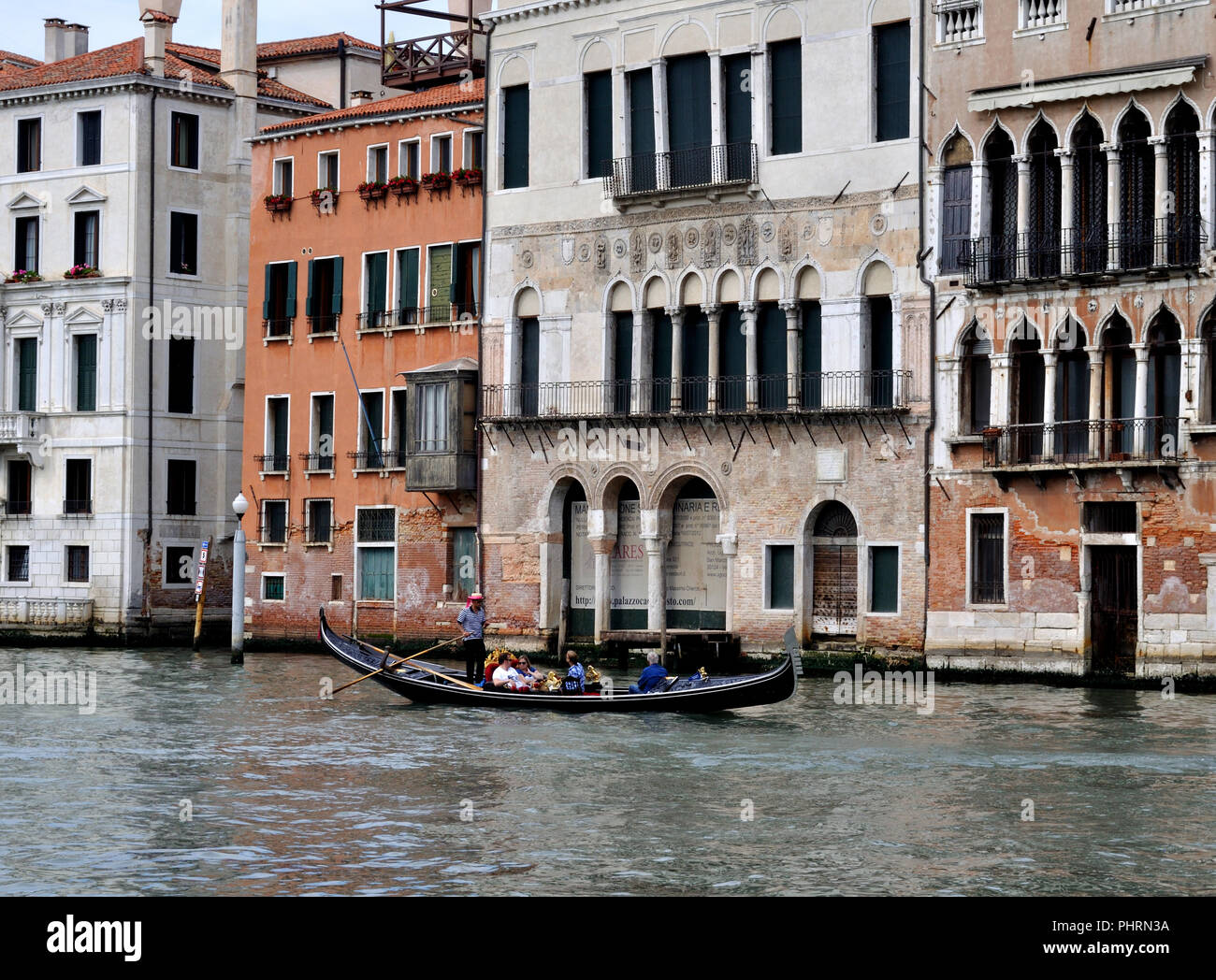 Una gondola passa alcuni dei palazzi sbiaditi di rivestimento del Canal Grande di Venezia Foto Stock