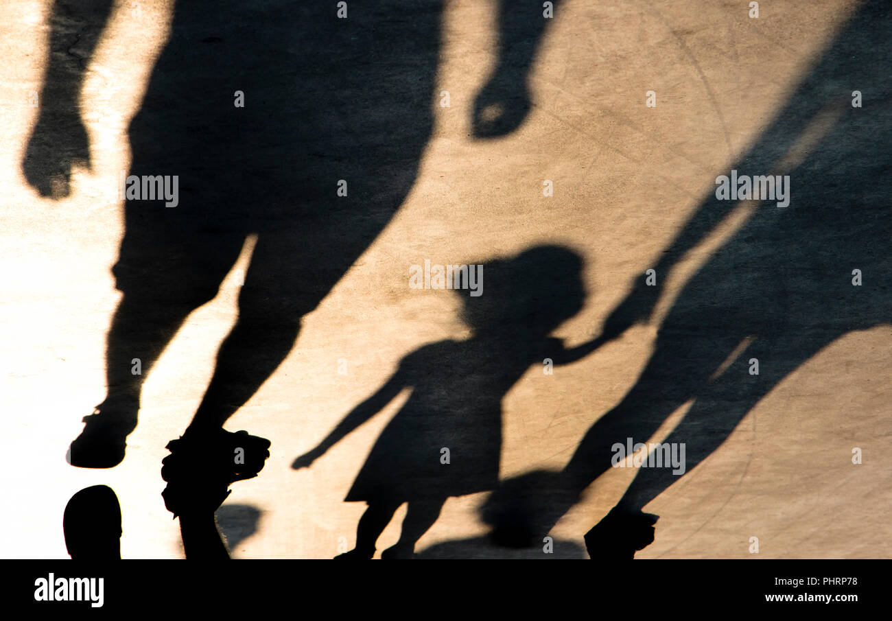 Silhouette di ombra di madre e figlia per mano mentre si cammina su misty estate promenade in seppia in bianco e nero Foto Stock