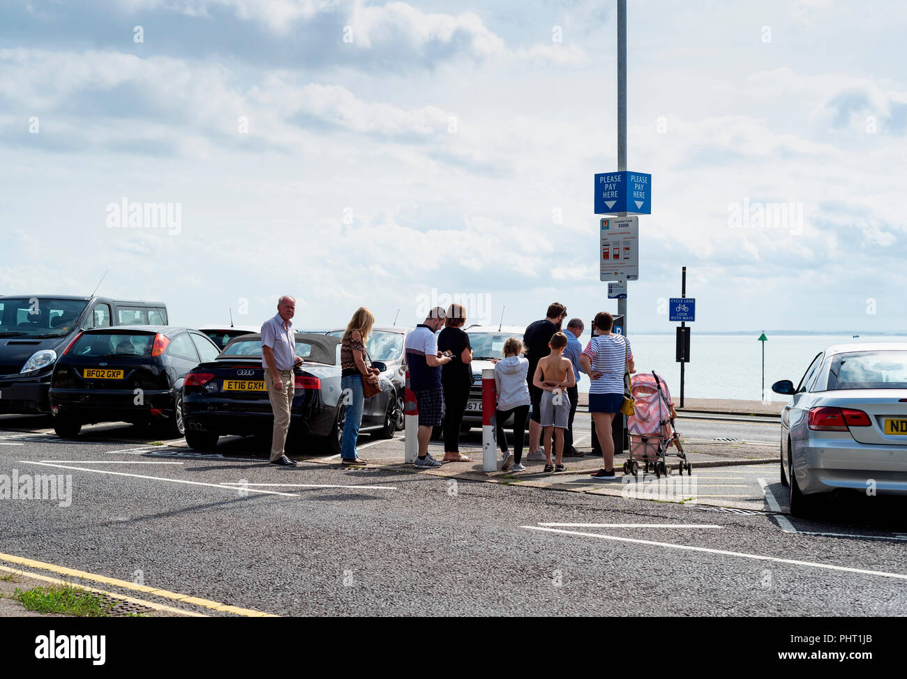 Persone queing in corrispondenza di una stazione a pagamento su una soleggiata giornata al mare. Foto Stock