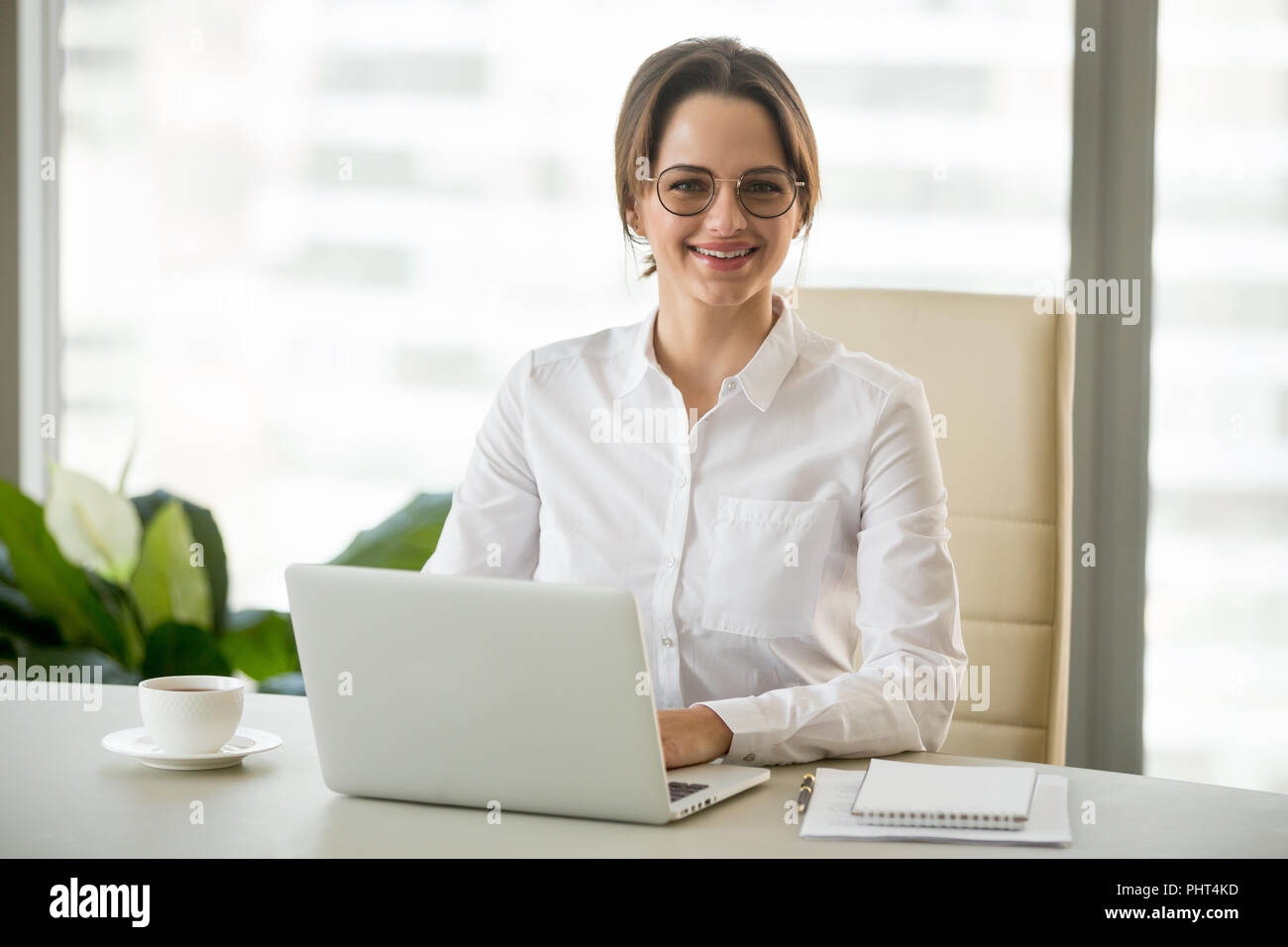 Sorridente imprenditrice millenario seduto alla scrivania con lapto Foto Stock