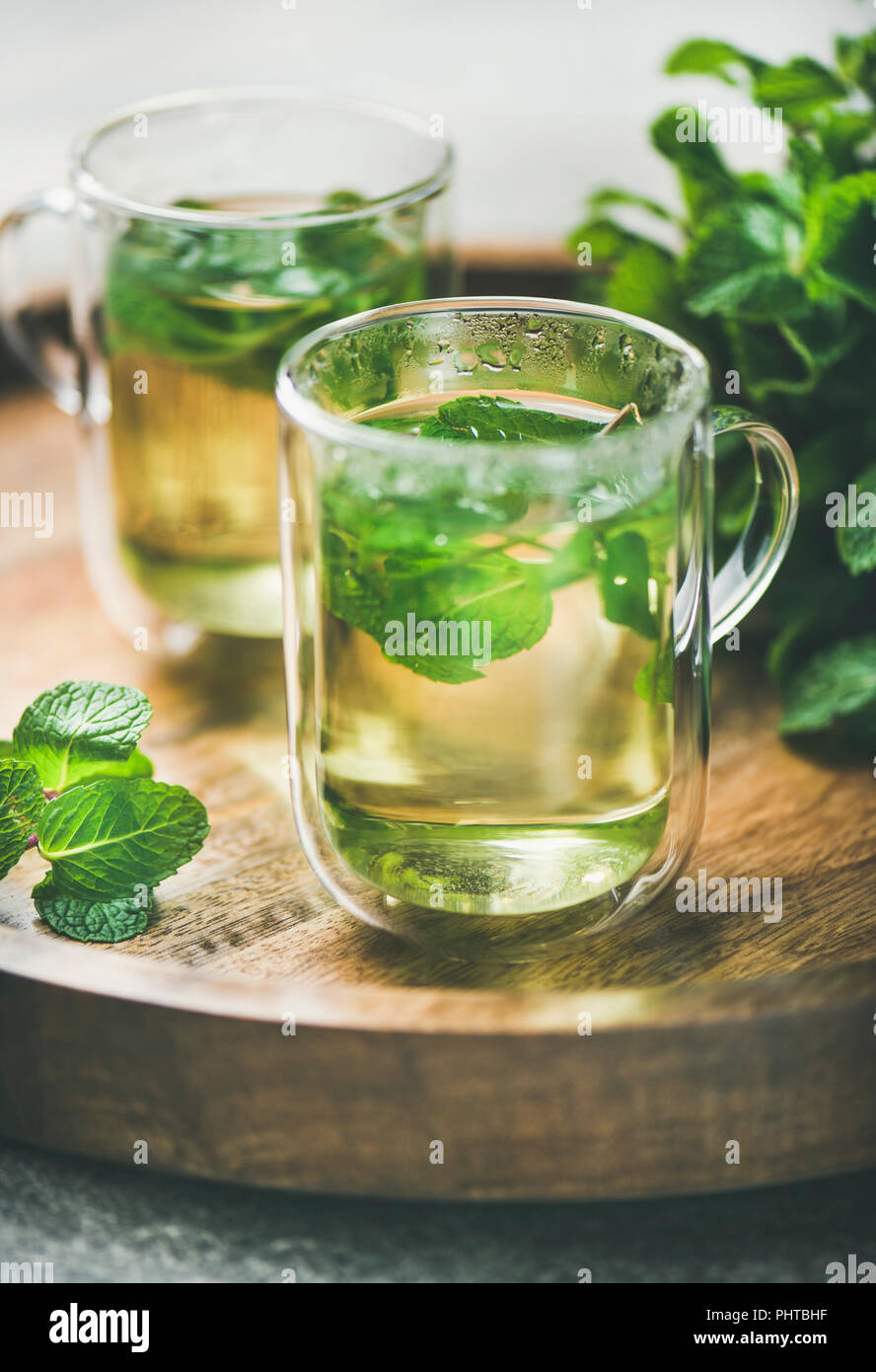 A base di erbe calde tè alla menta bevande in bicchieri di vetro sopra il vassoio in legno con giardino fresco menta, il fuoco selettivo Foto Stock