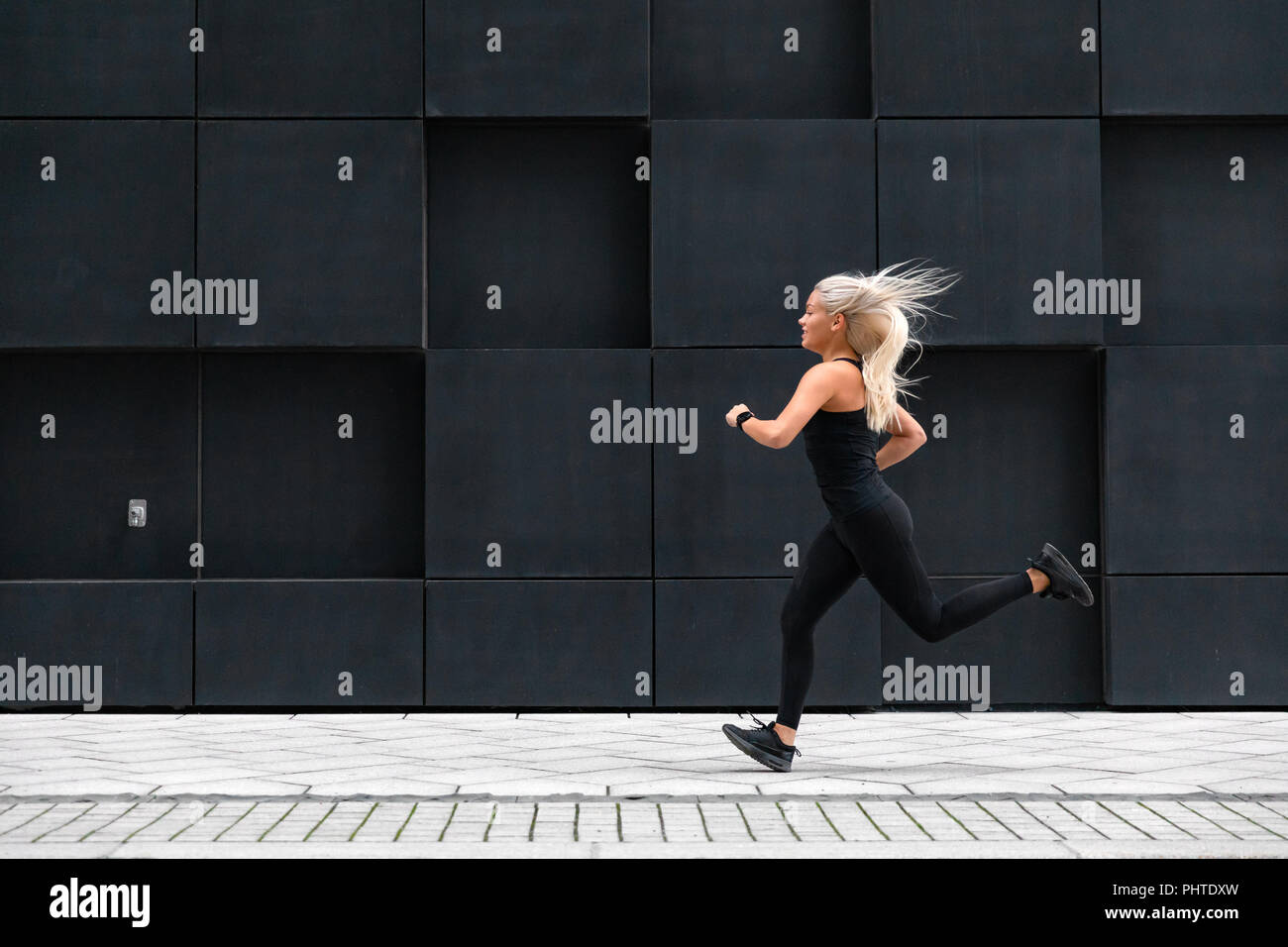 Vista laterale del giovane sportivo donna corre veloce minimalista in ambiente urbano Foto Stock