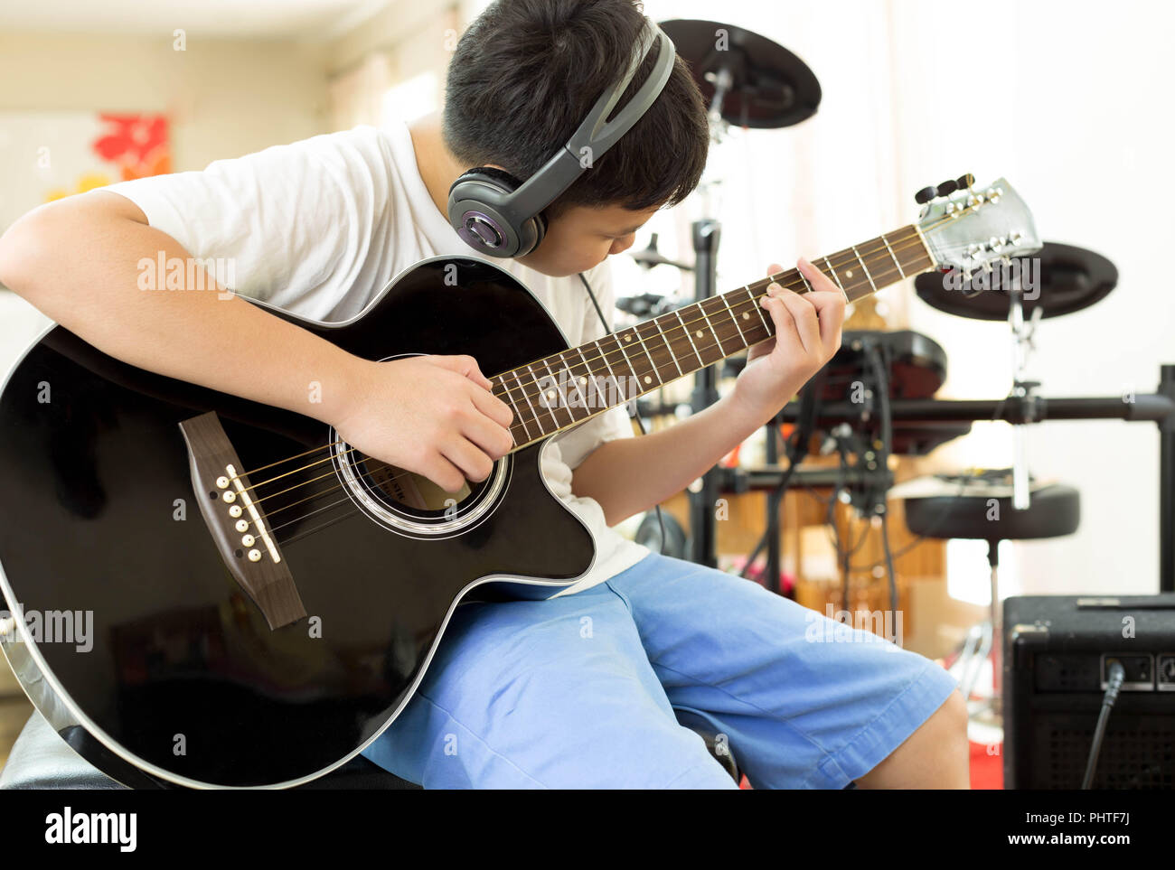 Ragazzo giocando una chitarra acustica con le cuffie sul Foto stock - Alamy