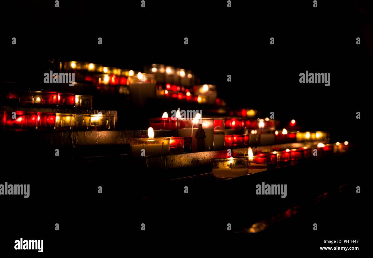 Le luci delle candele accese nel buio della chiesa cristiana Foto Stock