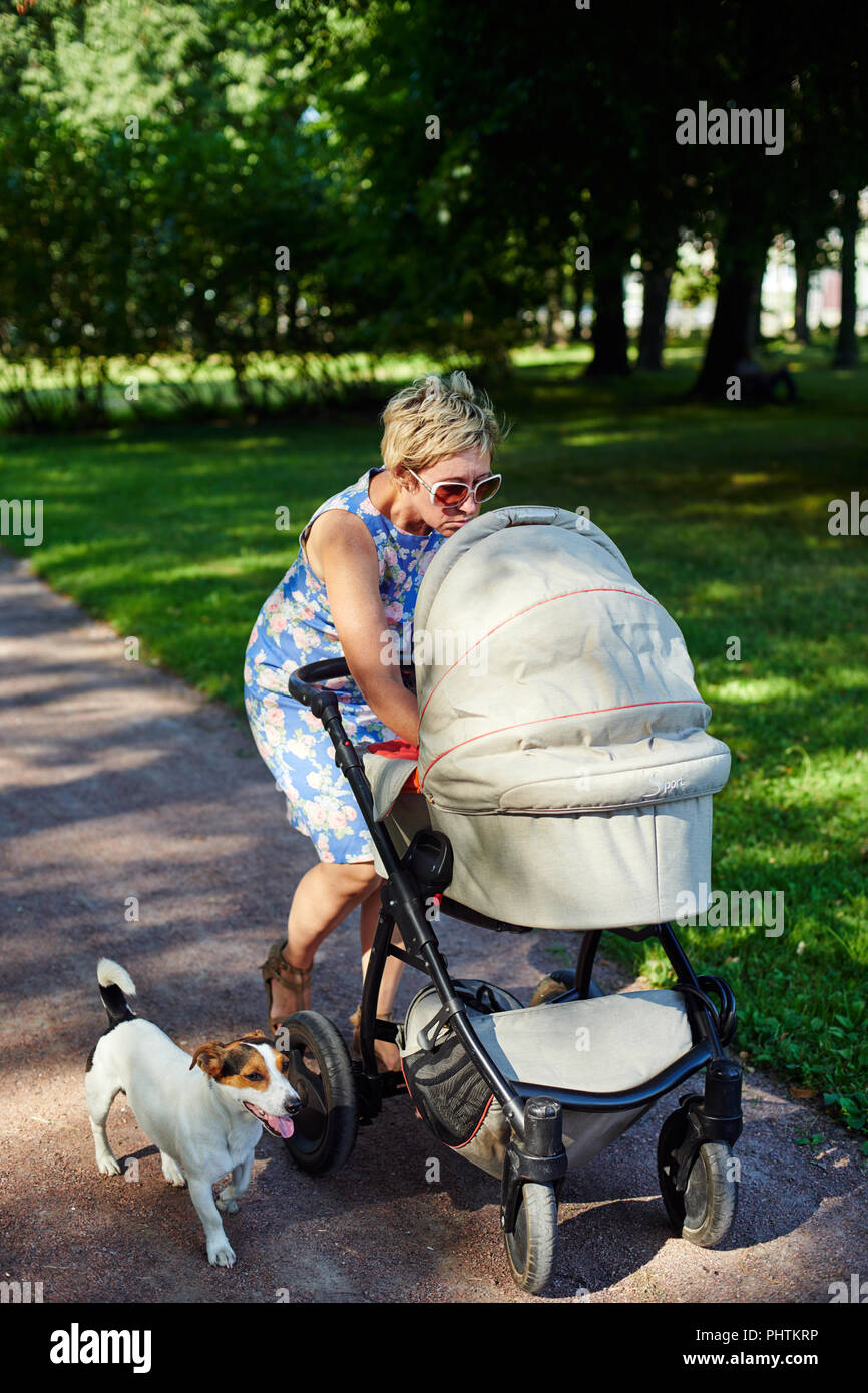 Donna passeggiate con il cane e il bambino trasporto Foto Stock