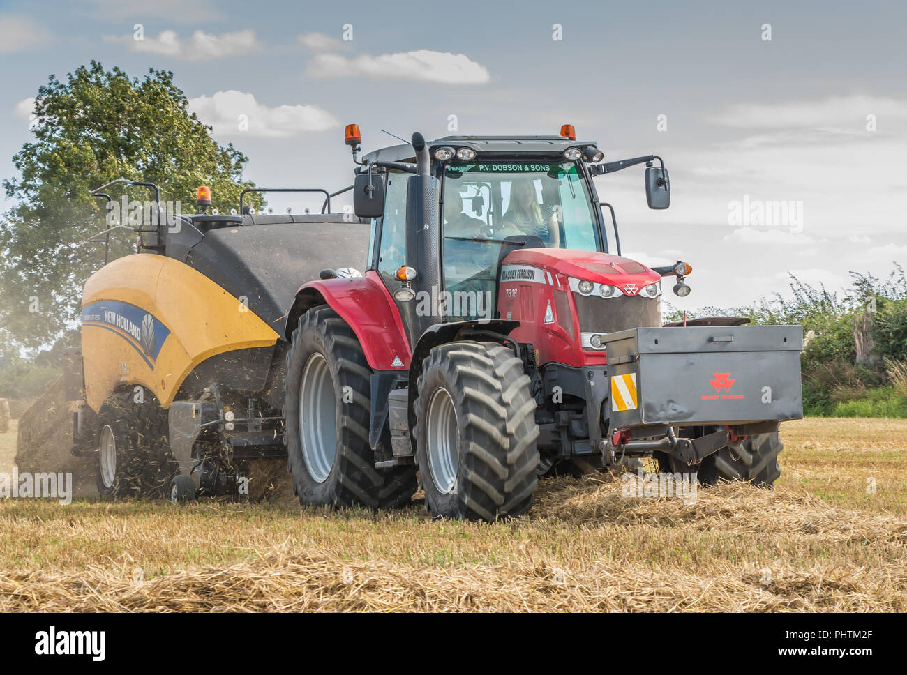 Un Massey Ferguson 7618 trattore e New Holland Bigbaler 1290 lavorando su paglia di orzo con una balla finito di essere scaricato Foto Stock