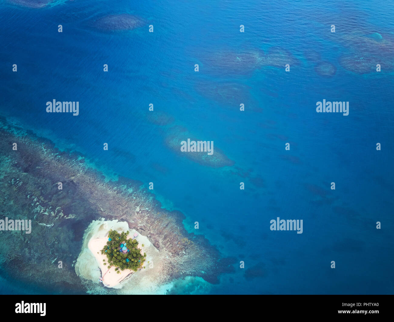 Mare blu acqua con barriere coralline e piccola isola Foto Stock
